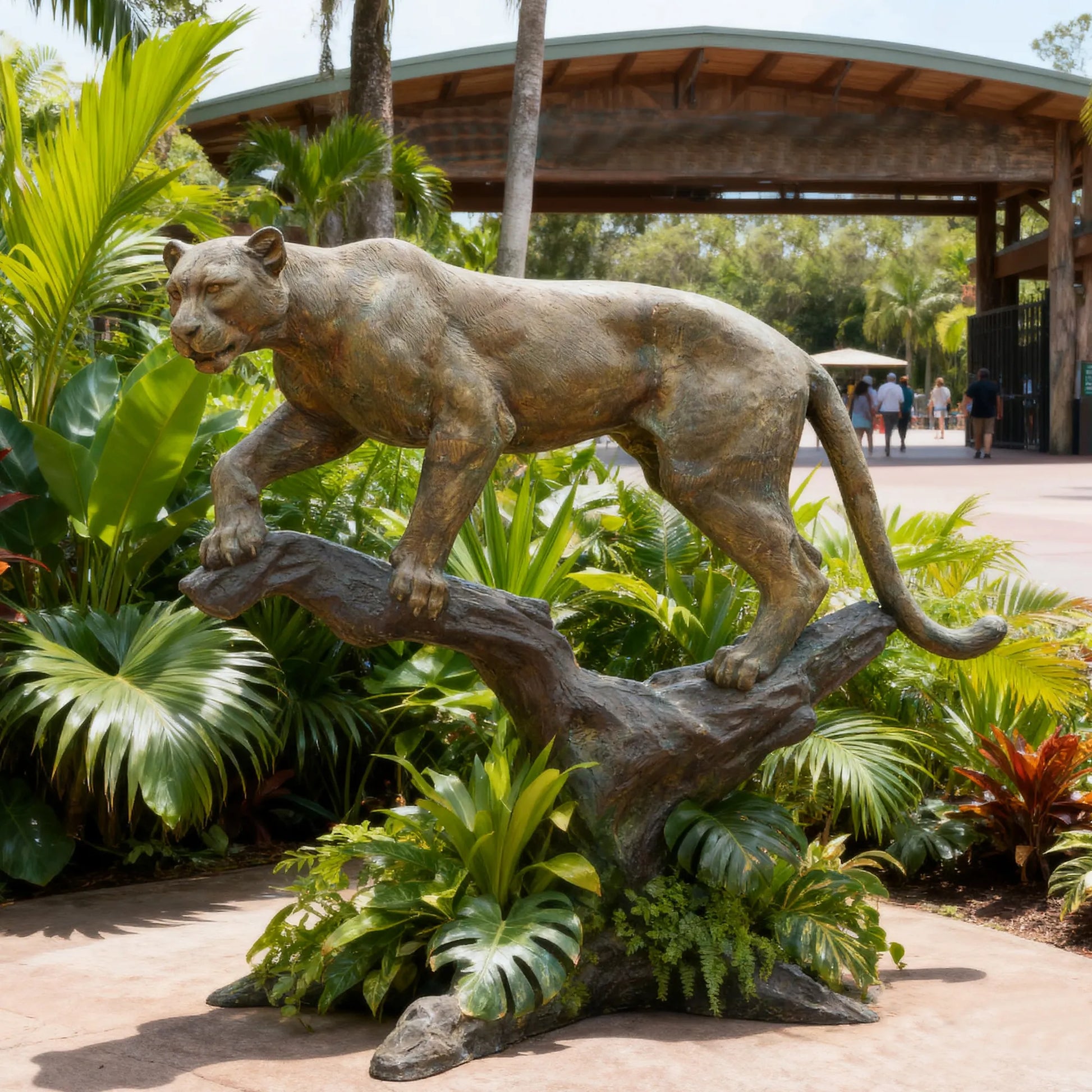 Full view of bronze panther sculpture standing on a tree branch showing lifelike pose.
