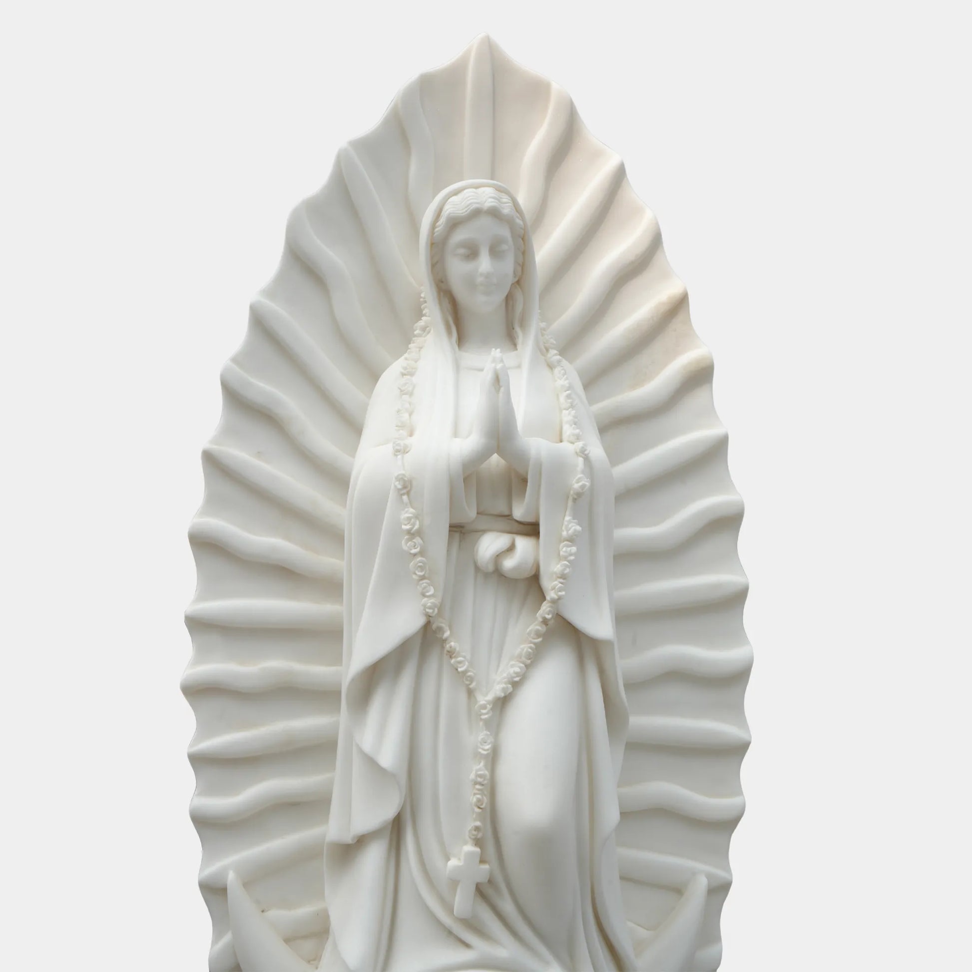 Marble sculpture of the Virgin Mary displayed in a softly lit chapel interior.