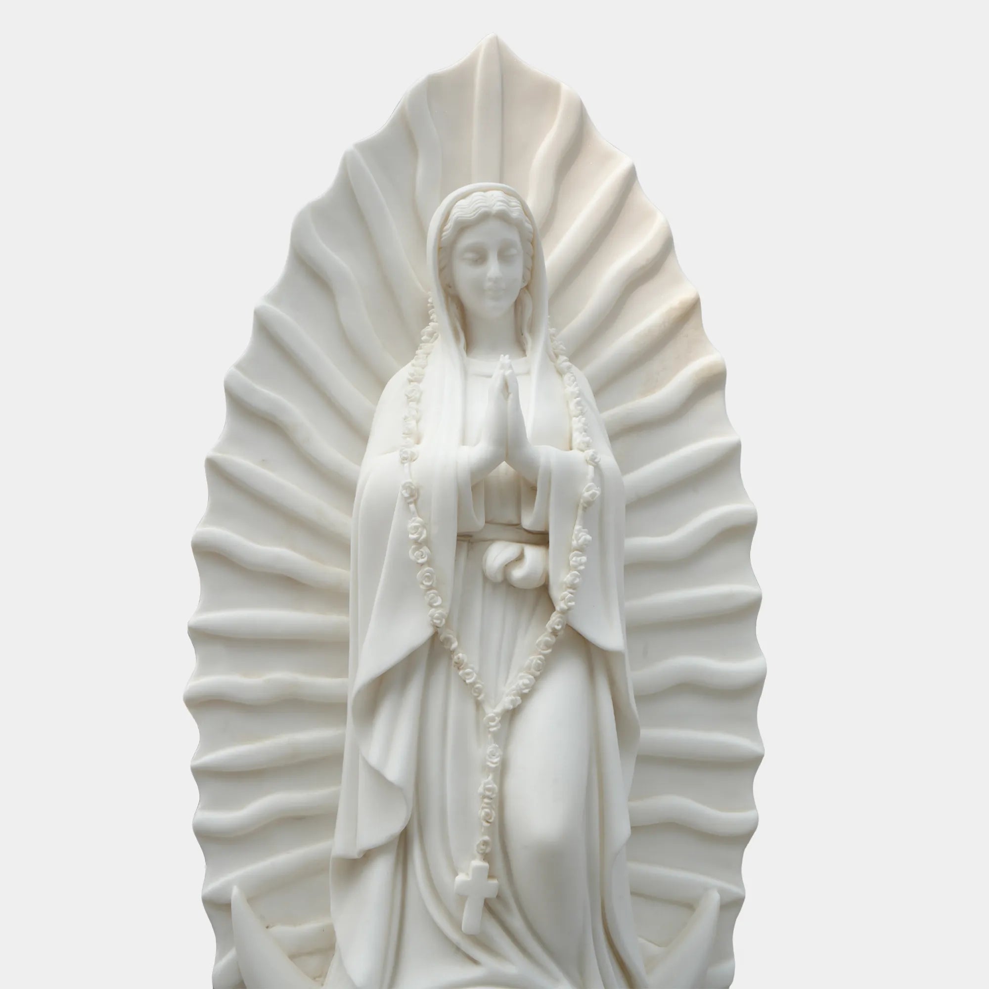 Marble sculpture of the Virgin Mary displayed in a softly lit chapel interior.