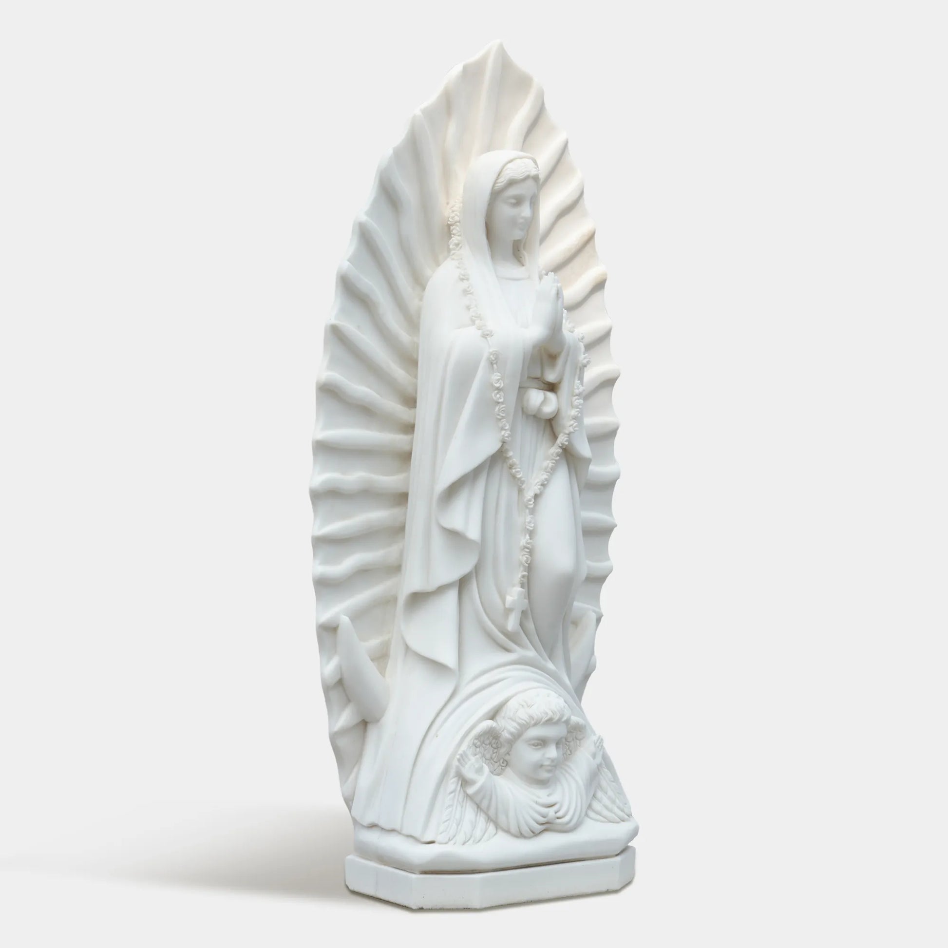 Marble sculpture of the Virgin Mary displayed in a softly lit chapel interior.