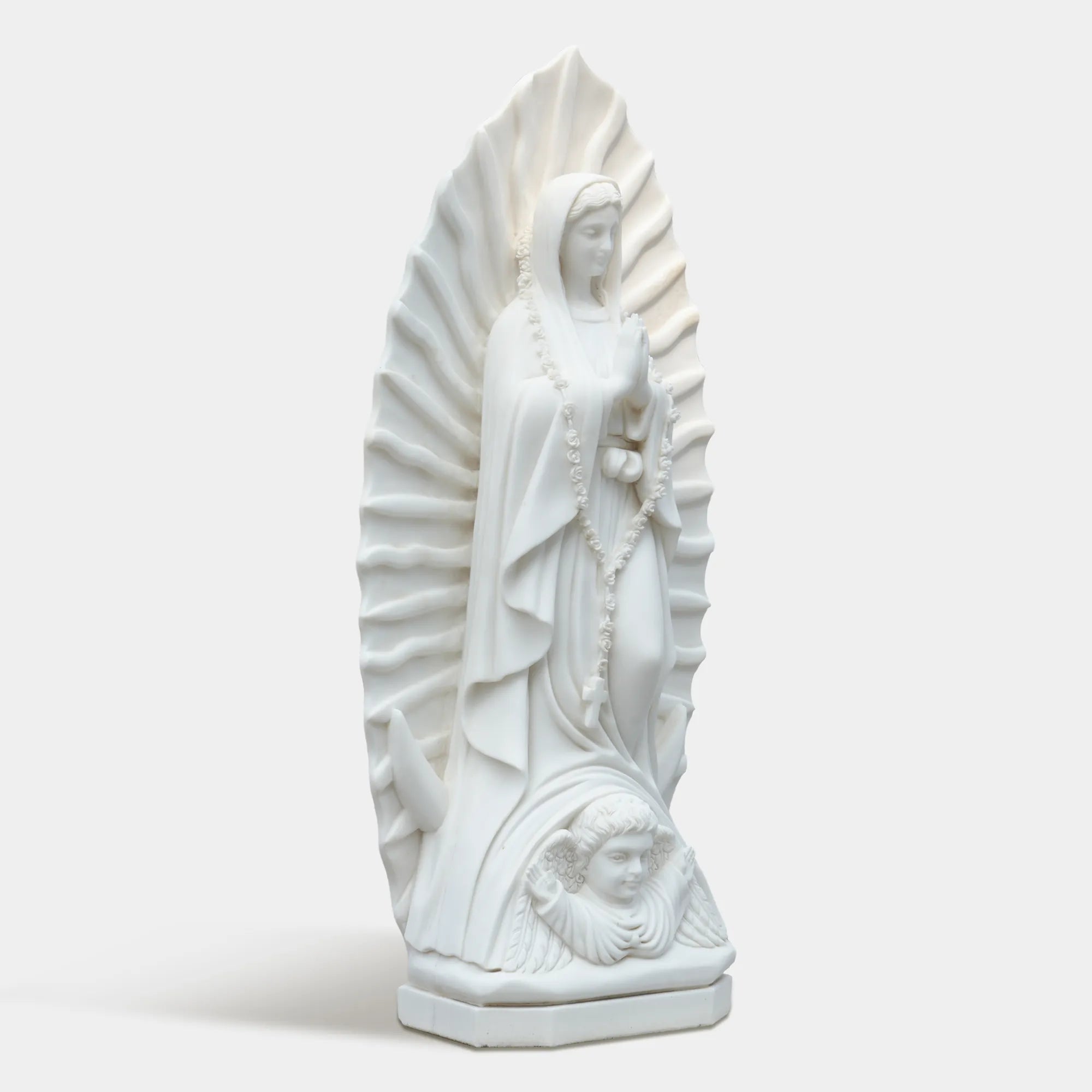 Marble sculpture of the Virgin Mary displayed in a softly lit chapel interior.