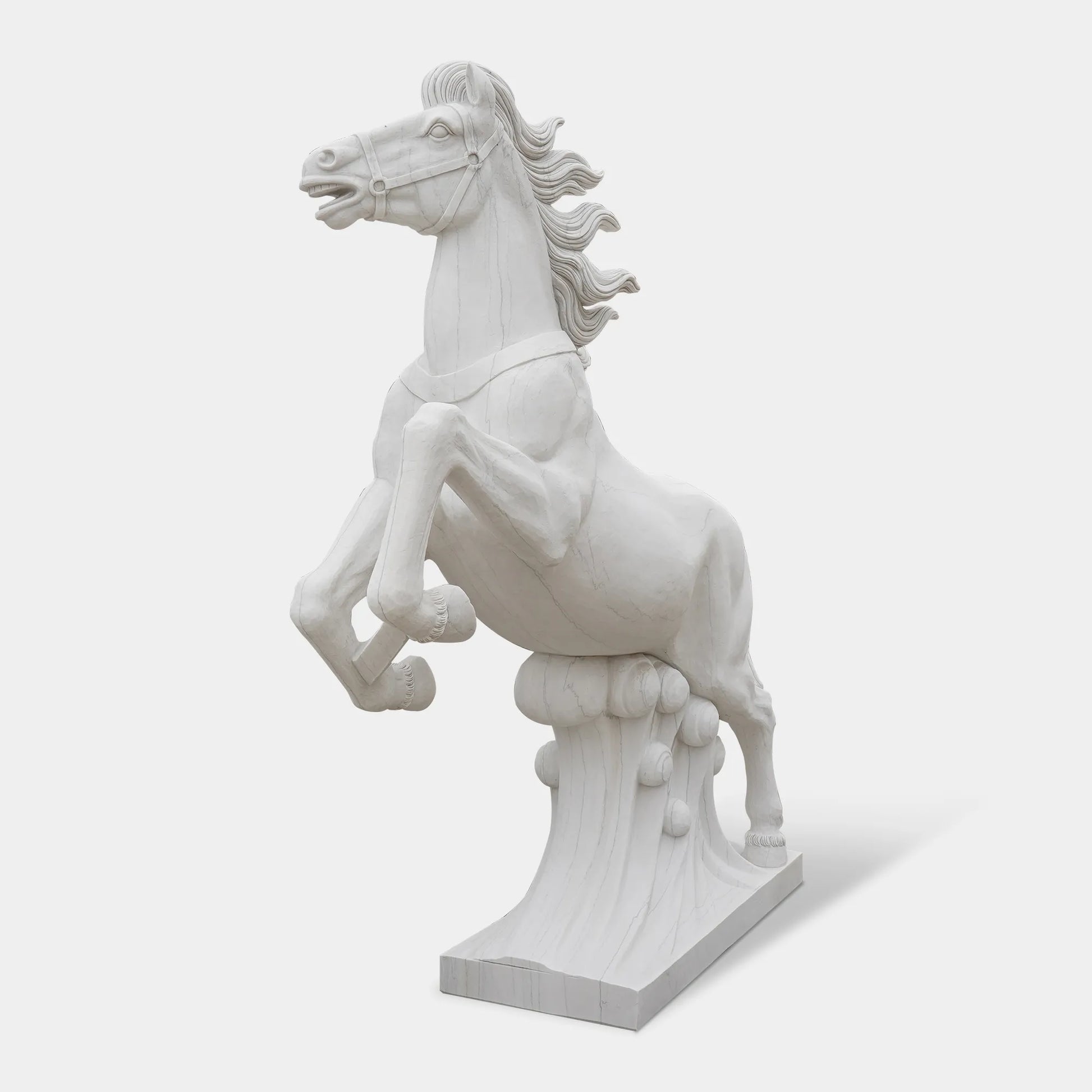 Marble horse sculpture displayed on a pedestal outside a neoclassical building under clear sky.