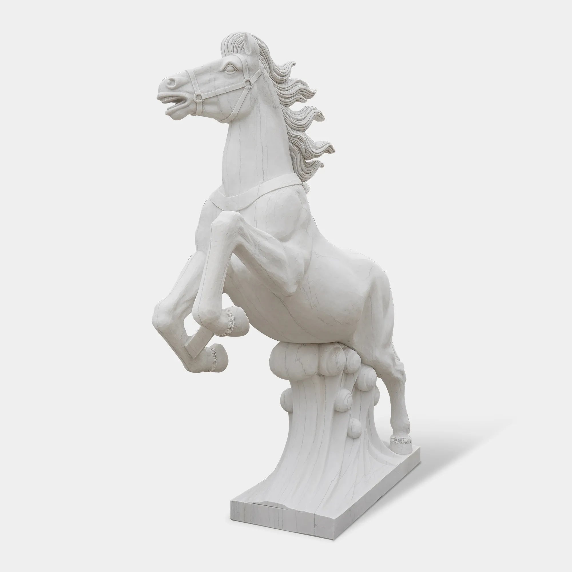 Marble horse sculpture displayed on a pedestal outside a neoclassical building under clear sky.