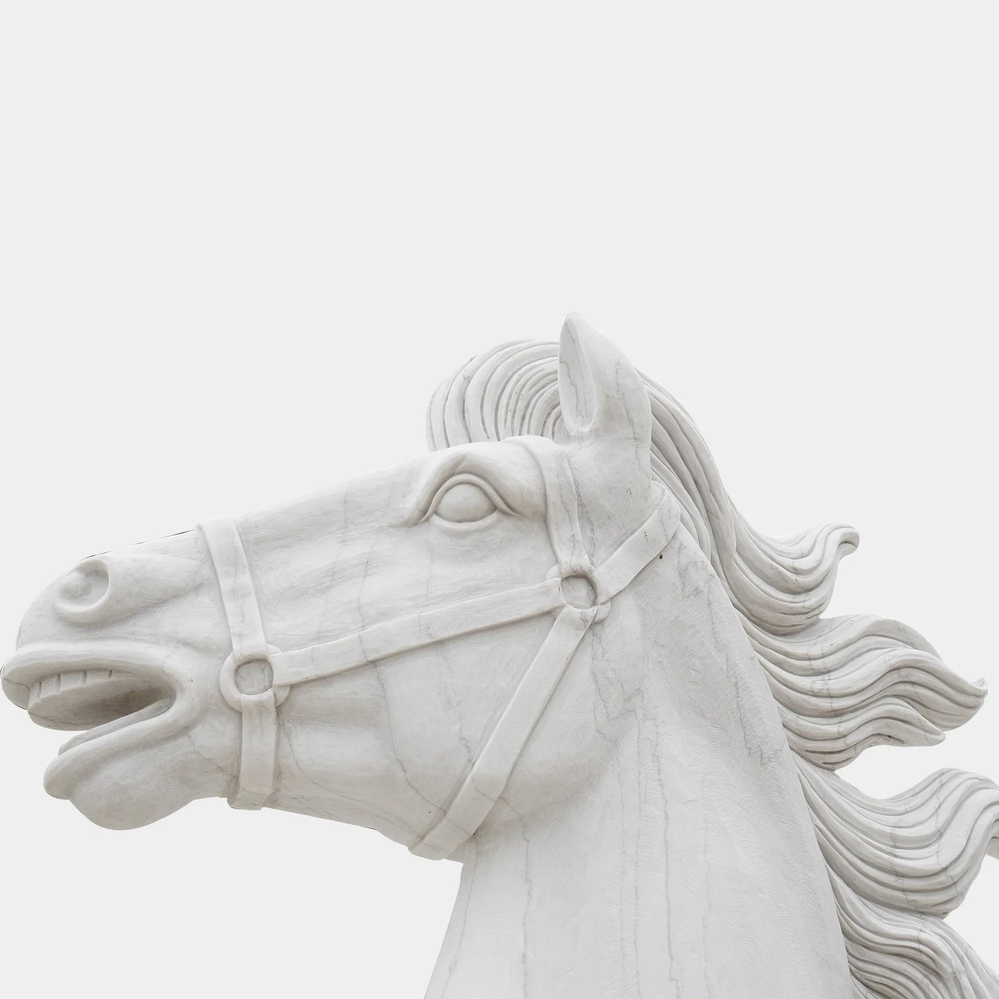 Marble horse sculpture displayed on a pedestal outside a neoclassical building under clear sky.