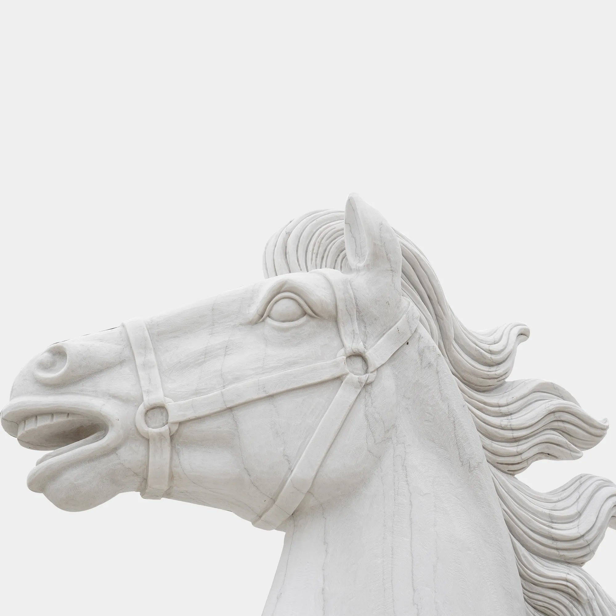 Marble horse sculpture displayed on a pedestal outside a neoclassical building under clear sky.