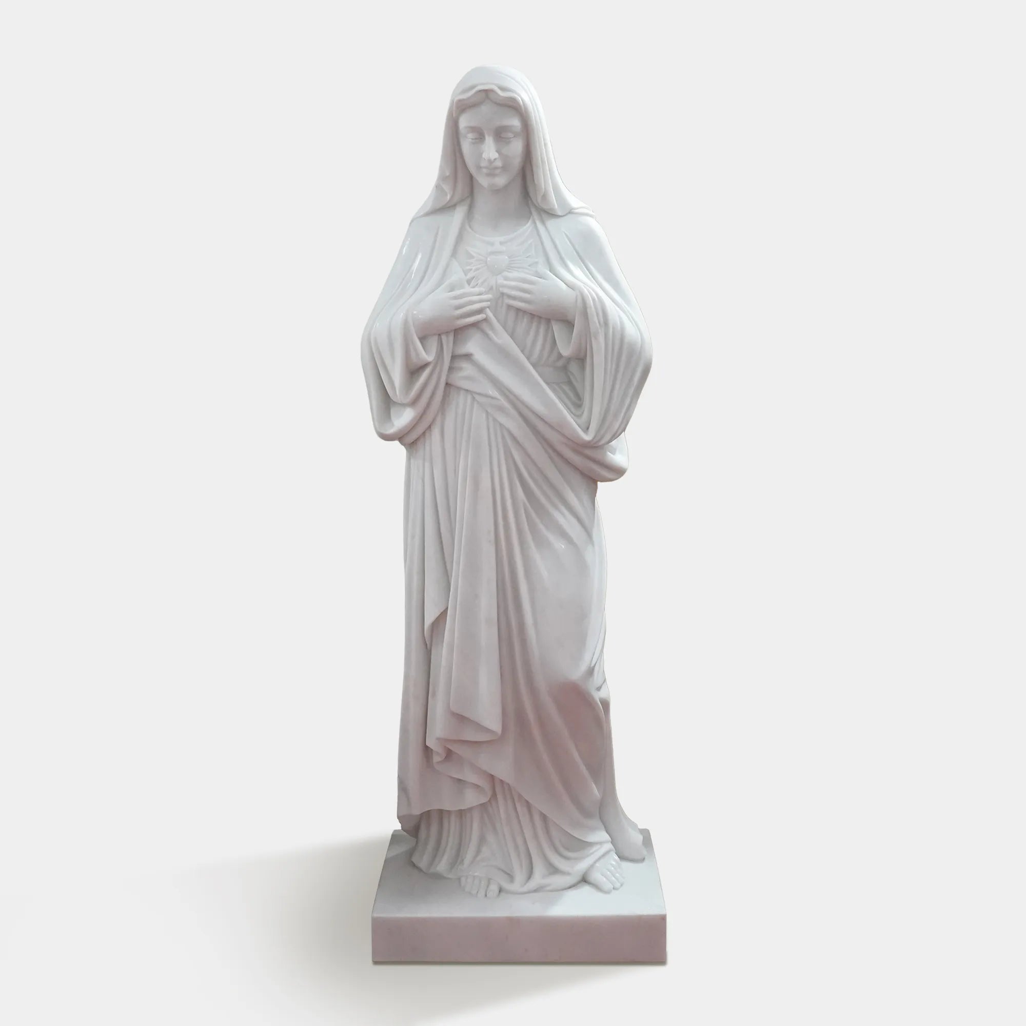 Marble Virgin Mary statue displayed in a peaceful garden surrounded by trees and classical white columns.