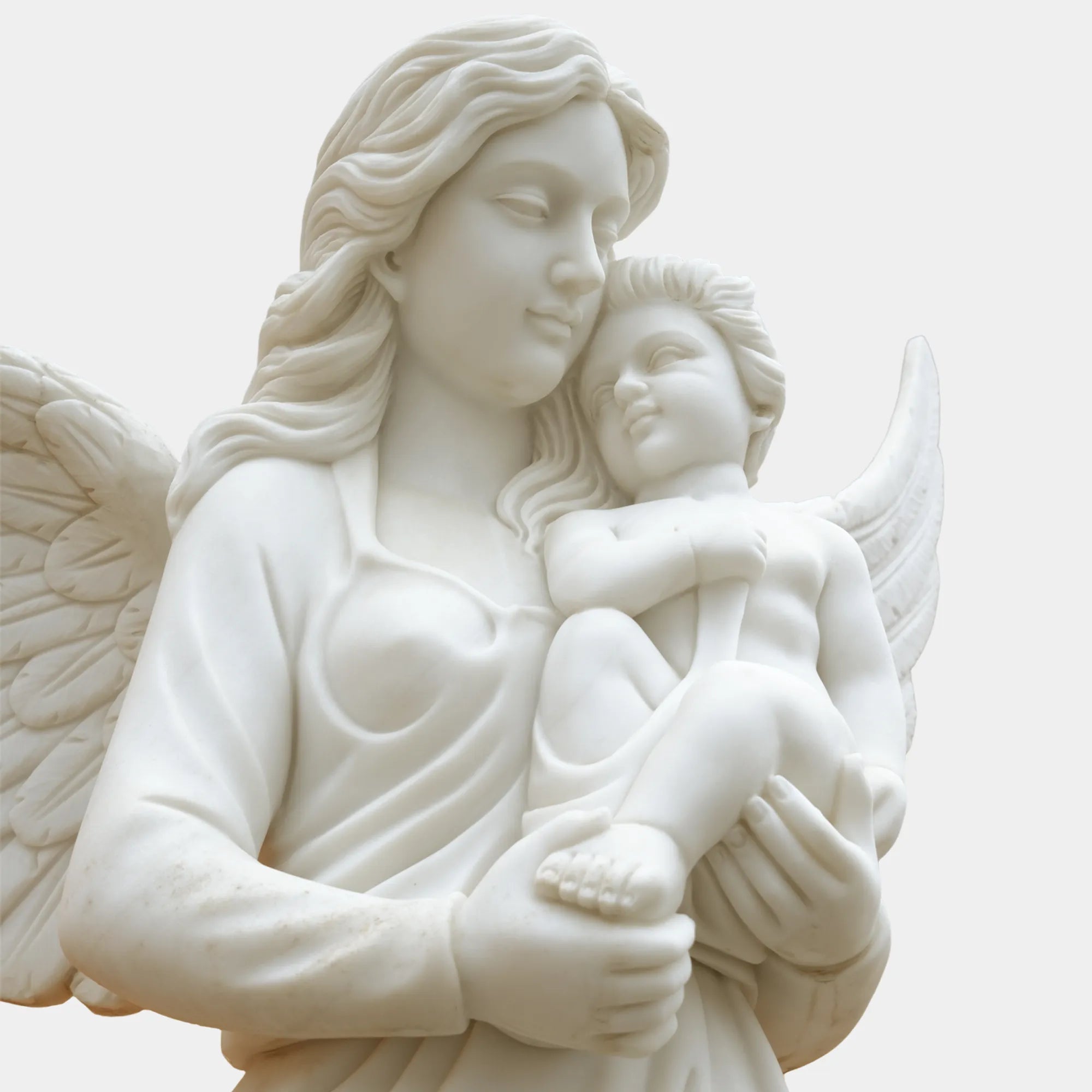 Outdoor marble angel with child sculpture displayed in a classical garden.