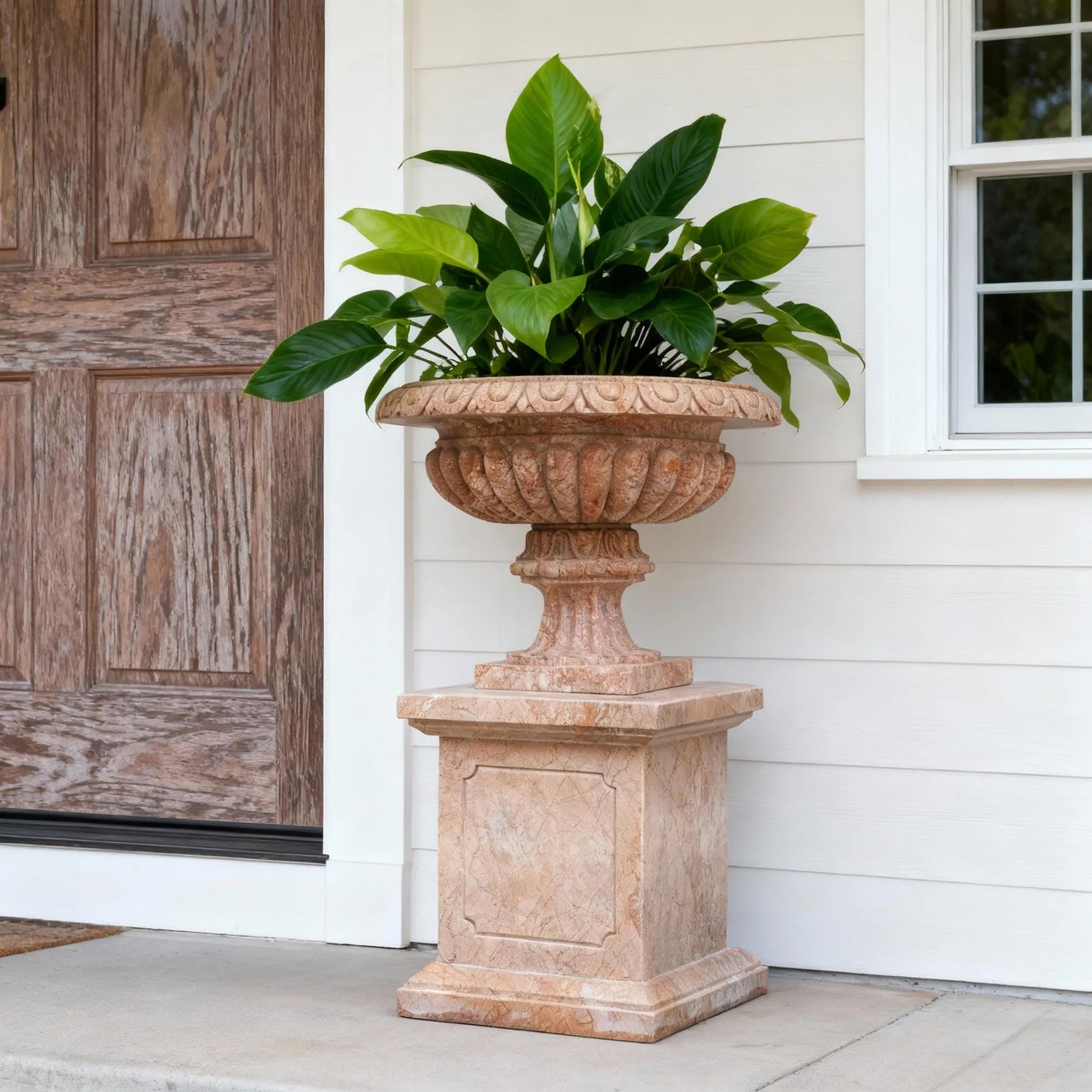 Warm-toned marble planter sculpture with elegant carved details and classic shape.