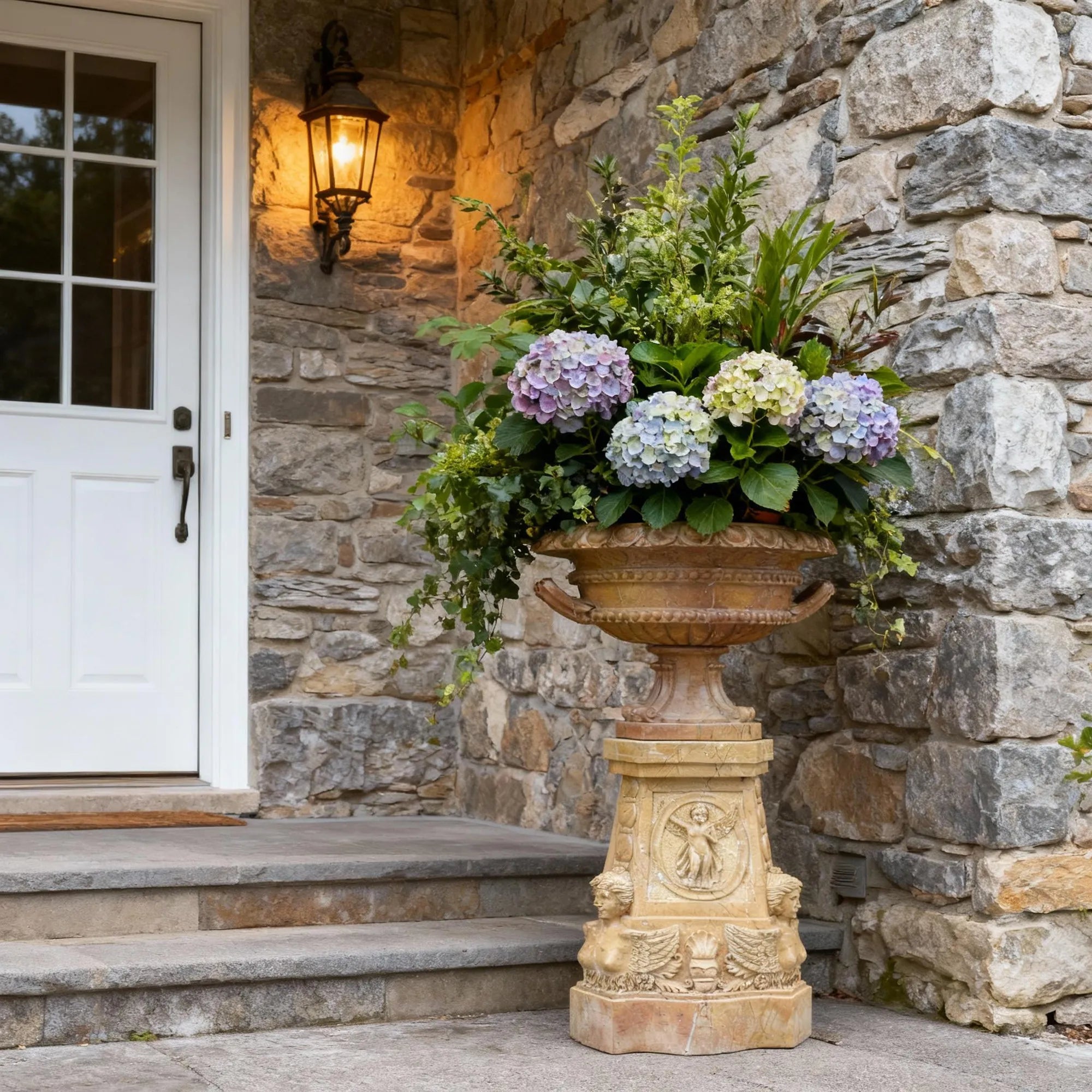 Marble planter sculpture placed near a stone villa entrance with blooming hydrangeas.