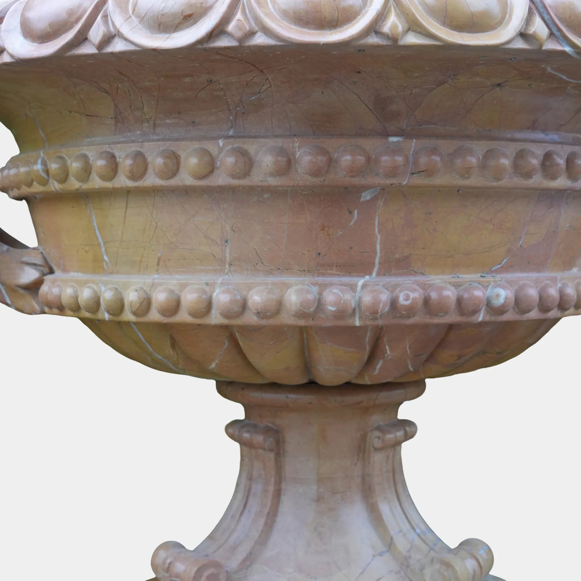 Marble planter sculpture placed near a stone villa entrance with blooming hydrangeas.