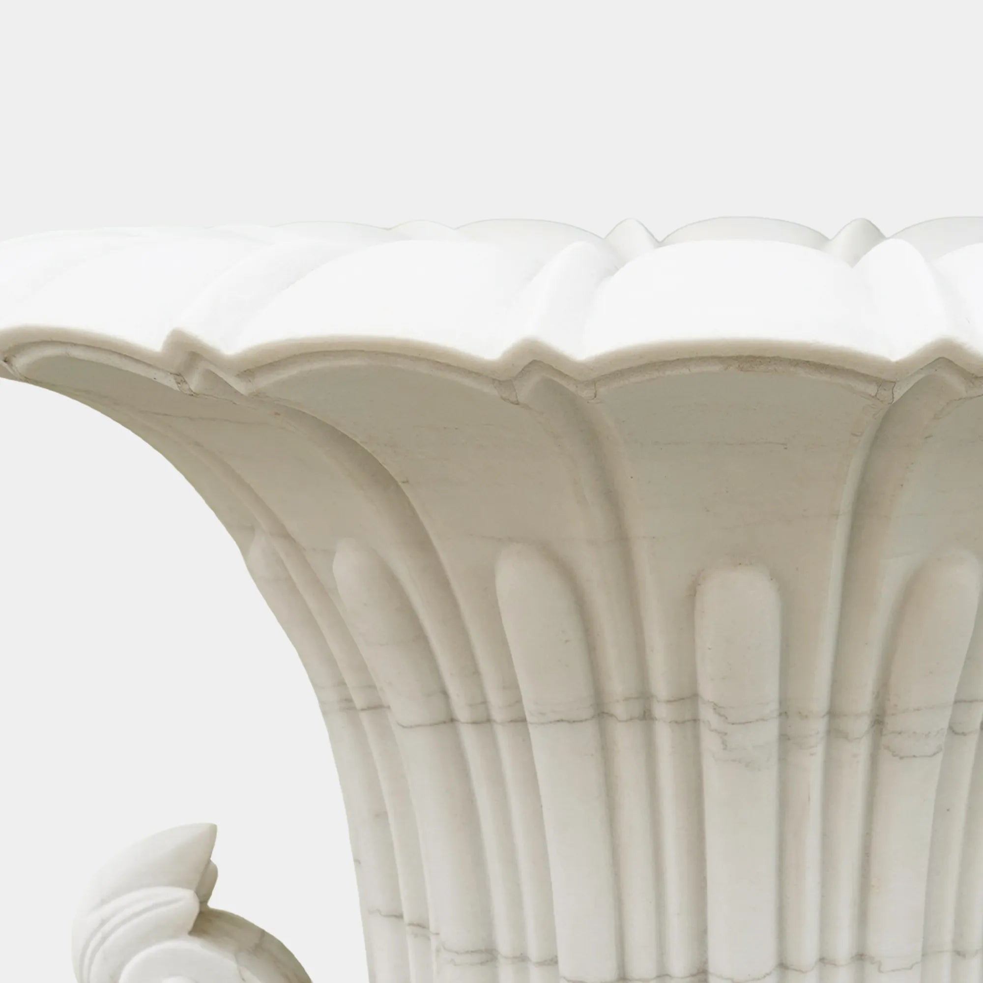 Pair of marble planter sculptures with white flowers framing a garden pathway.