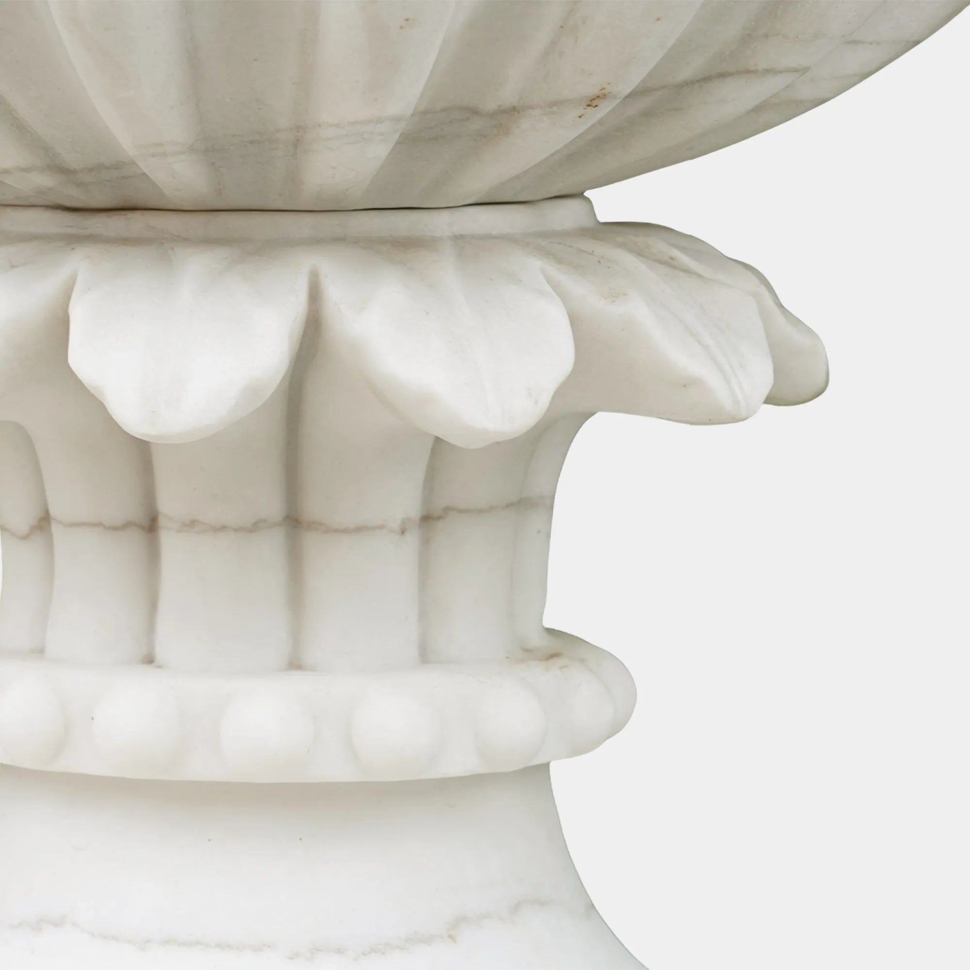 Pair of marble planter sculptures with white flowers framing a garden pathway.