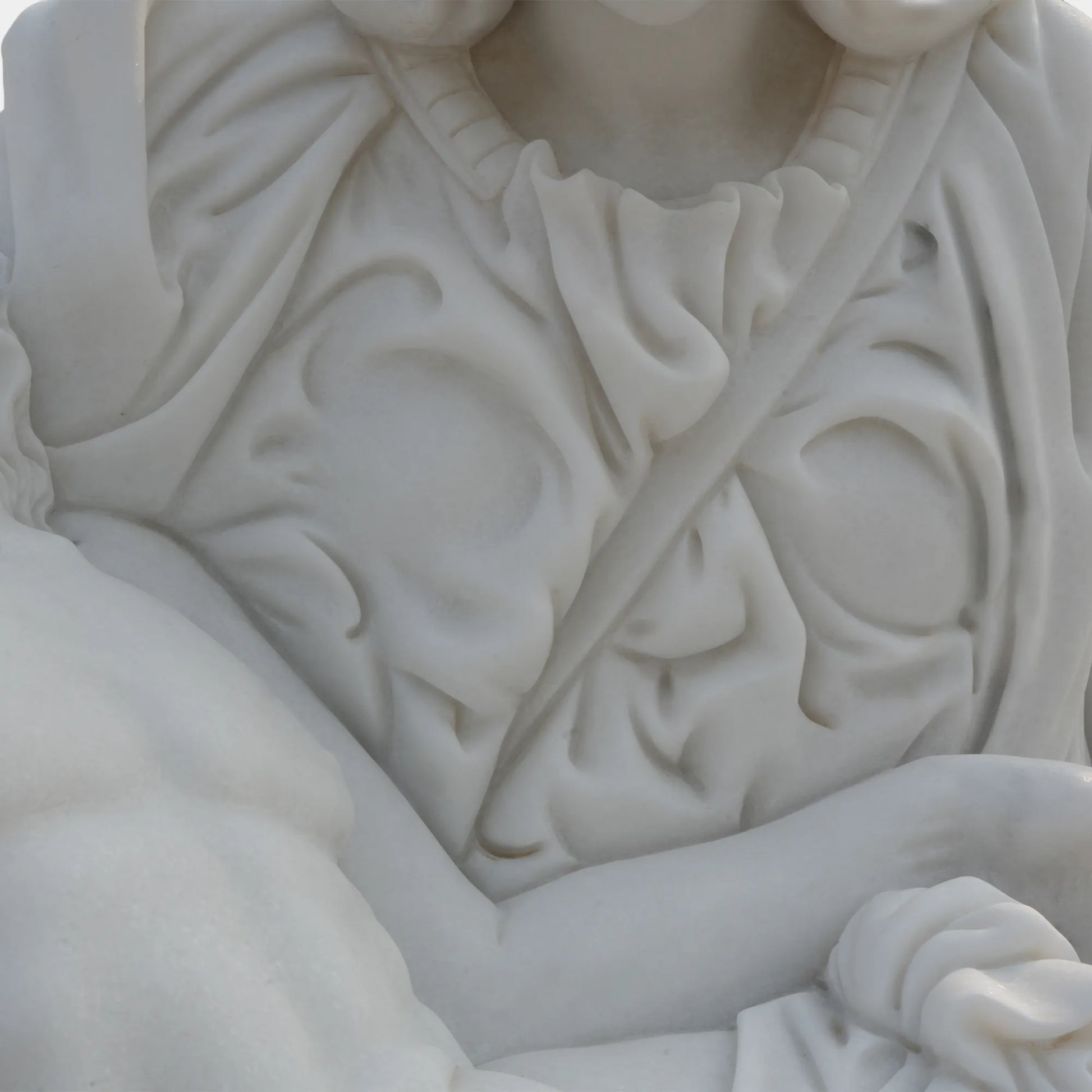 Marble Pietà sculpture placed in a tranquil garden with sunlight filtering through trees.