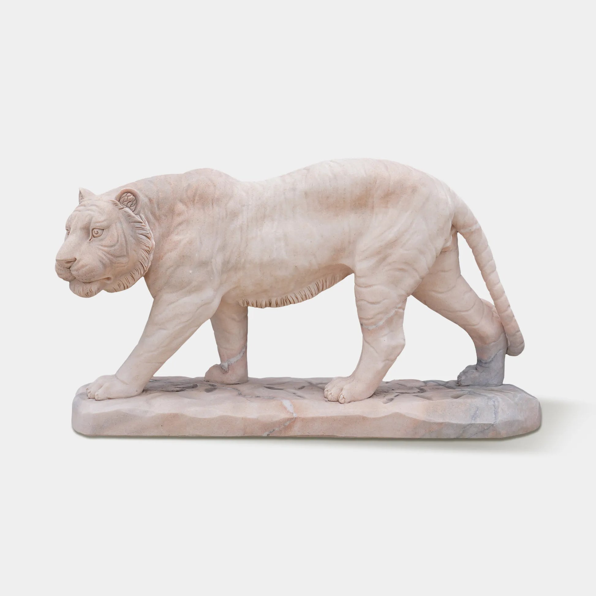 Elegant marble tiger sculpture displayed in a luxury garden at sunset.