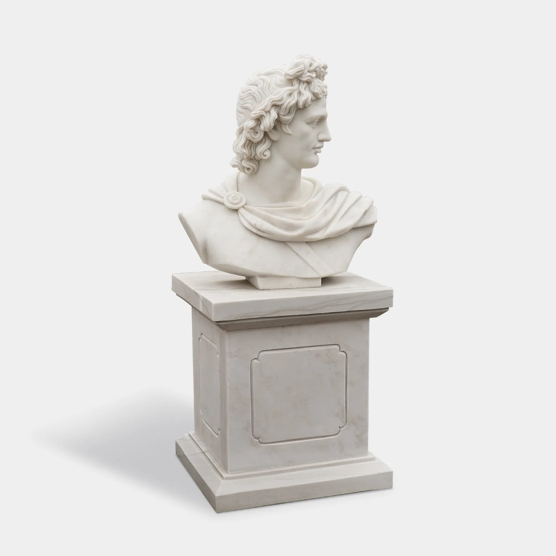 Apollo marble bust on matching pedestal photographed in a gallery interior.