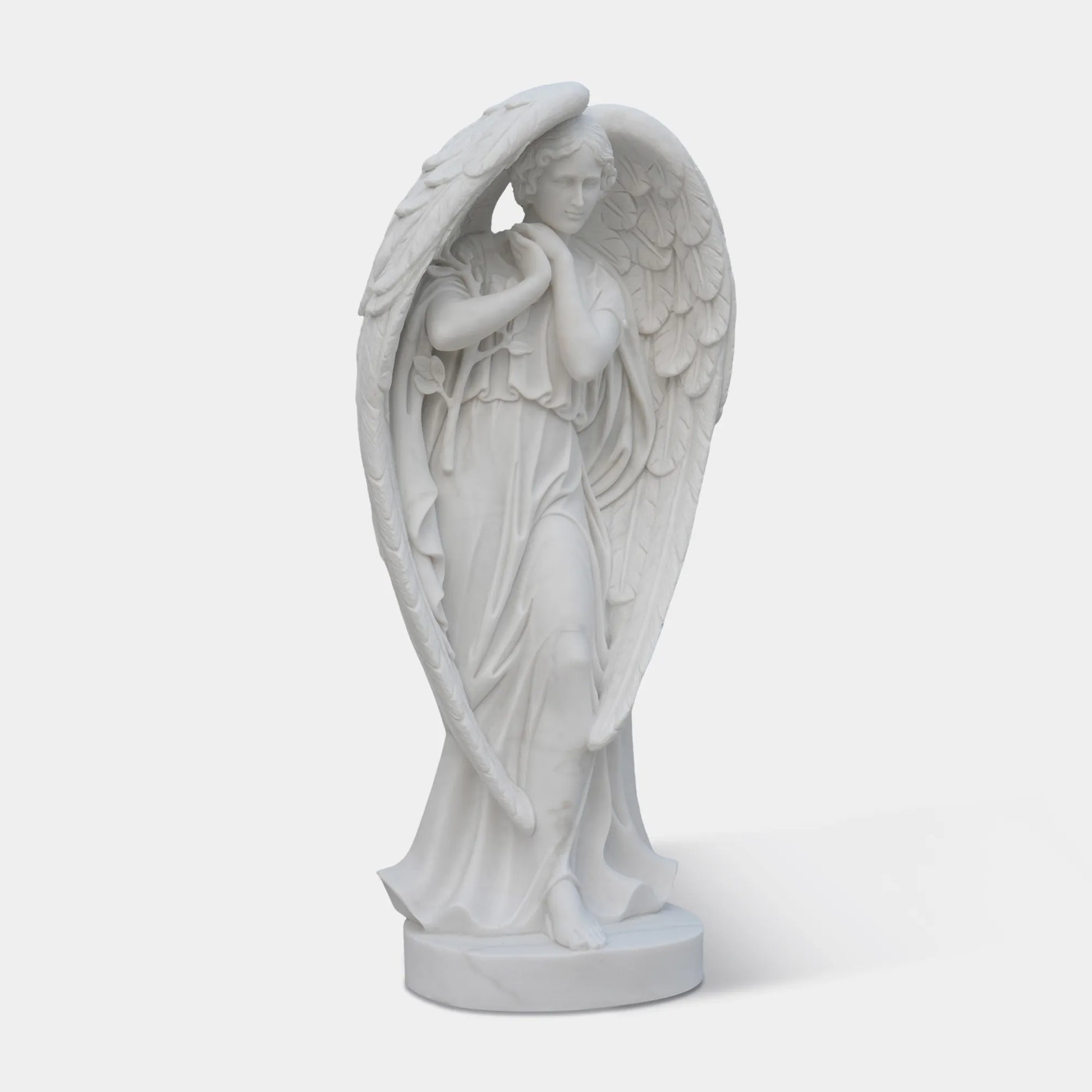 White marble angel statue standing on round base.