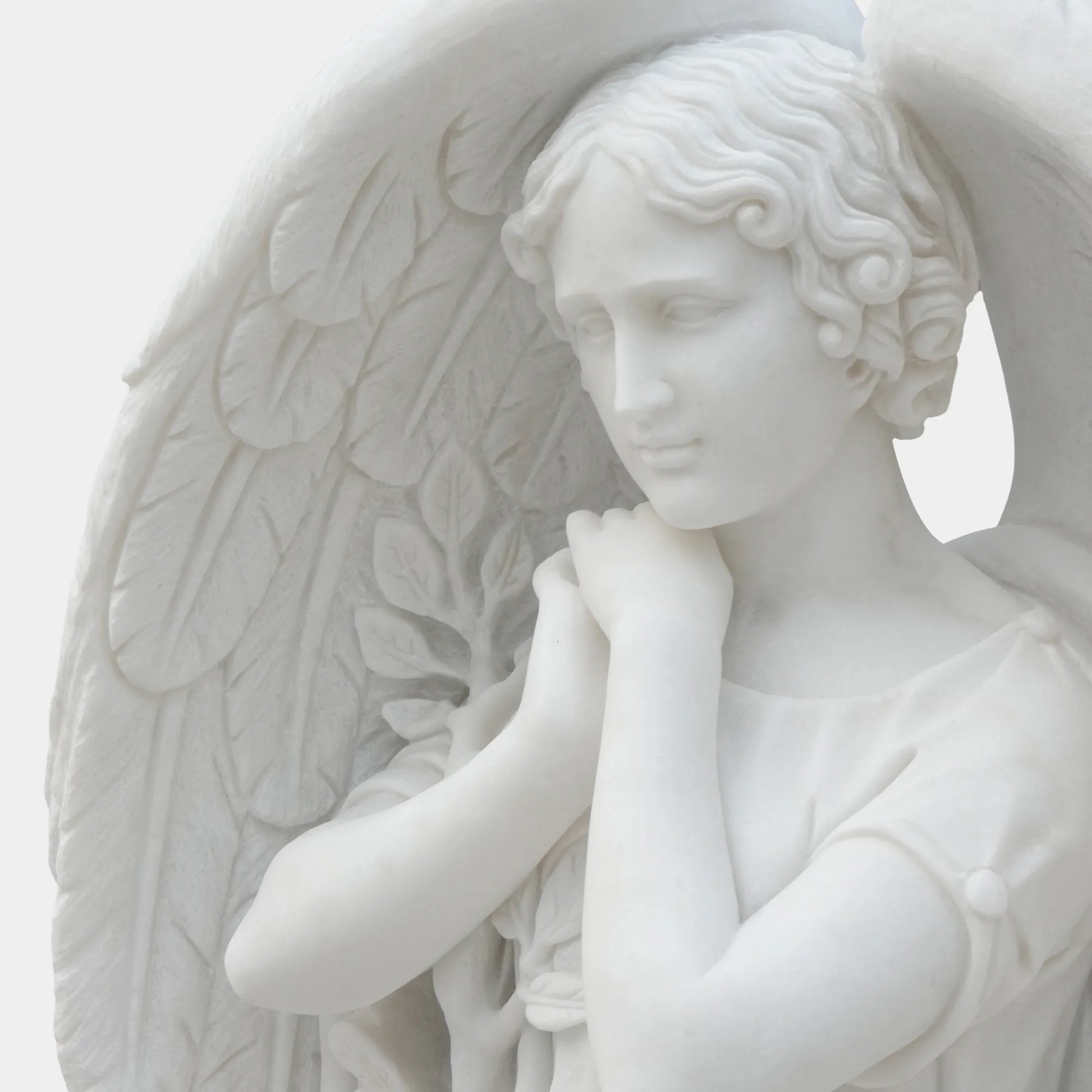 White marble angel statue standing on round base.