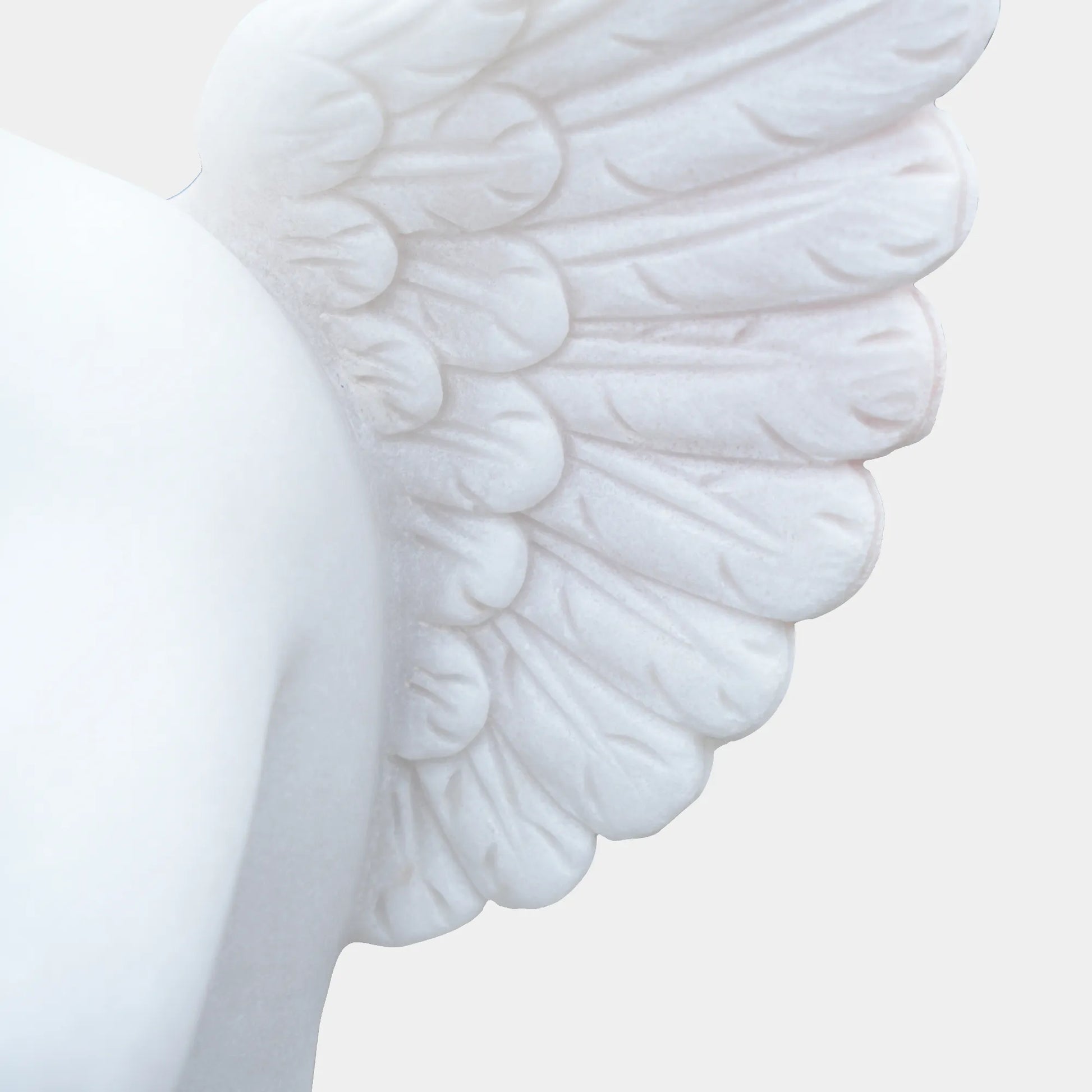 White marble cherub angel statue playing a flute on a pedestal in the garden path. 