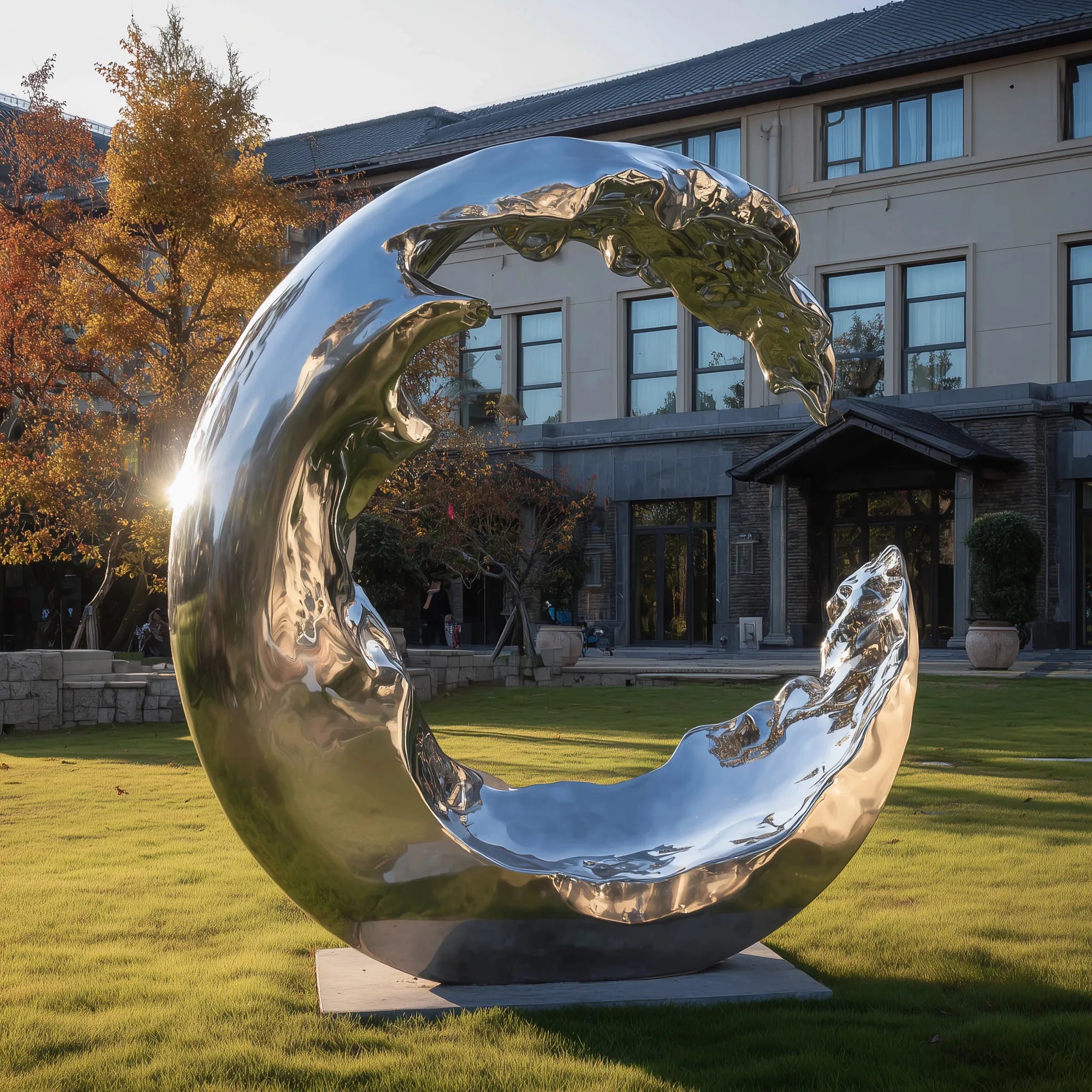 Mirror-finish stainless steel wave sculpture positioned in a landscaped outdoor area.