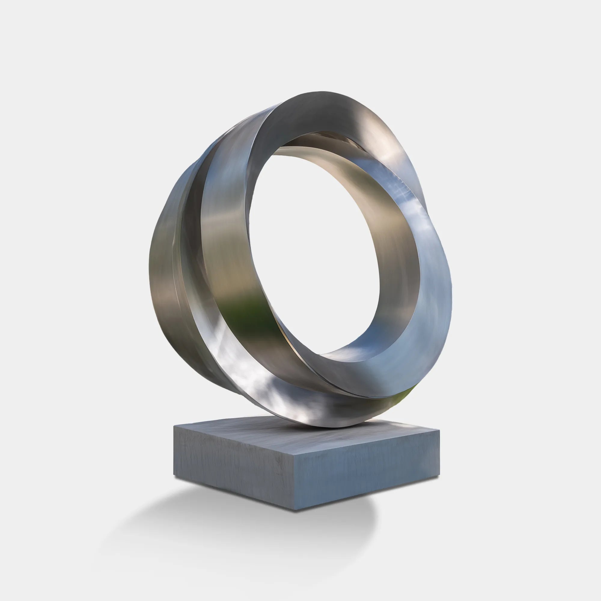 Stainless steel layered ring sculpture on a square base displayed outdoors.