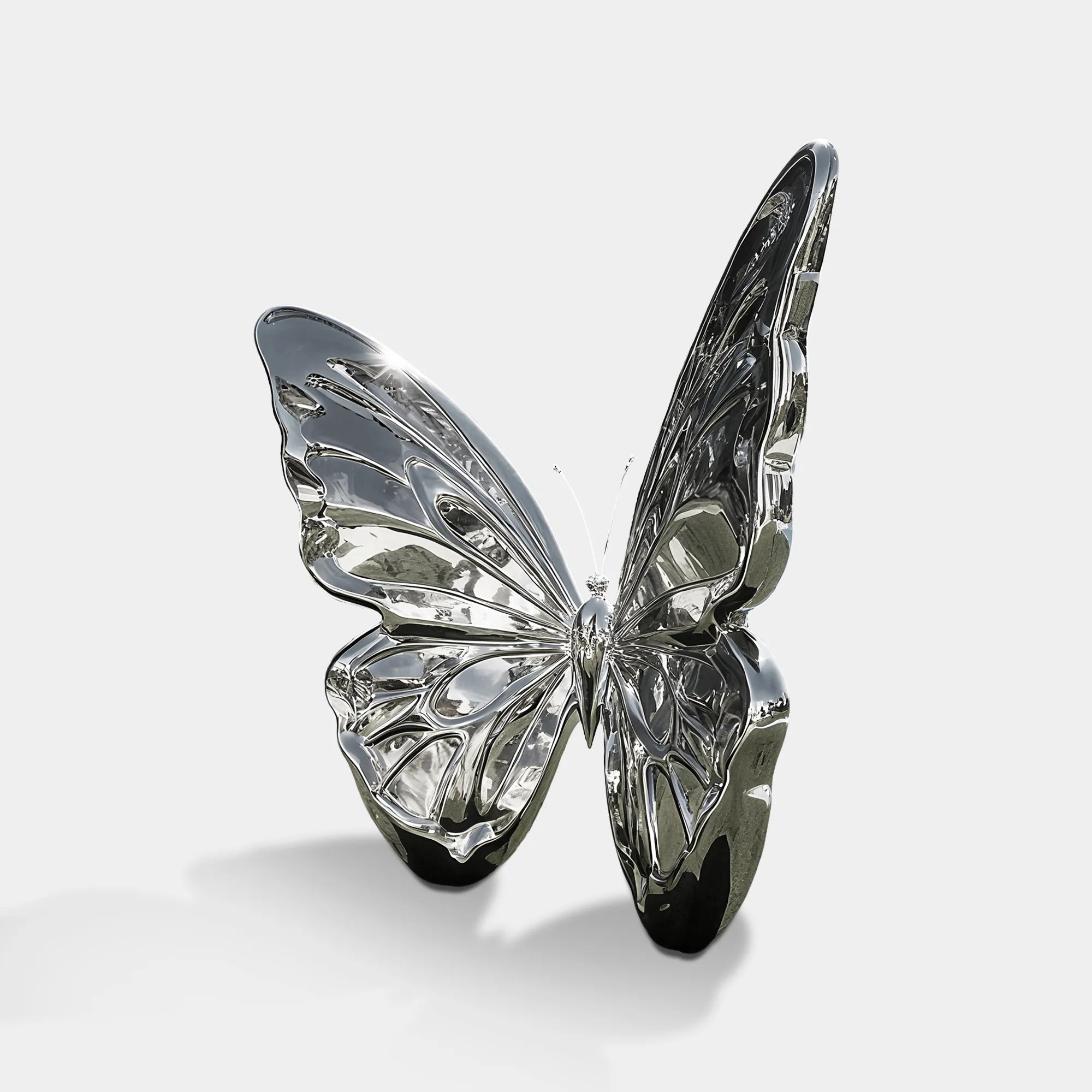 Mirror polished stainless steel butterfly sculpture installed on lawn near modern building.