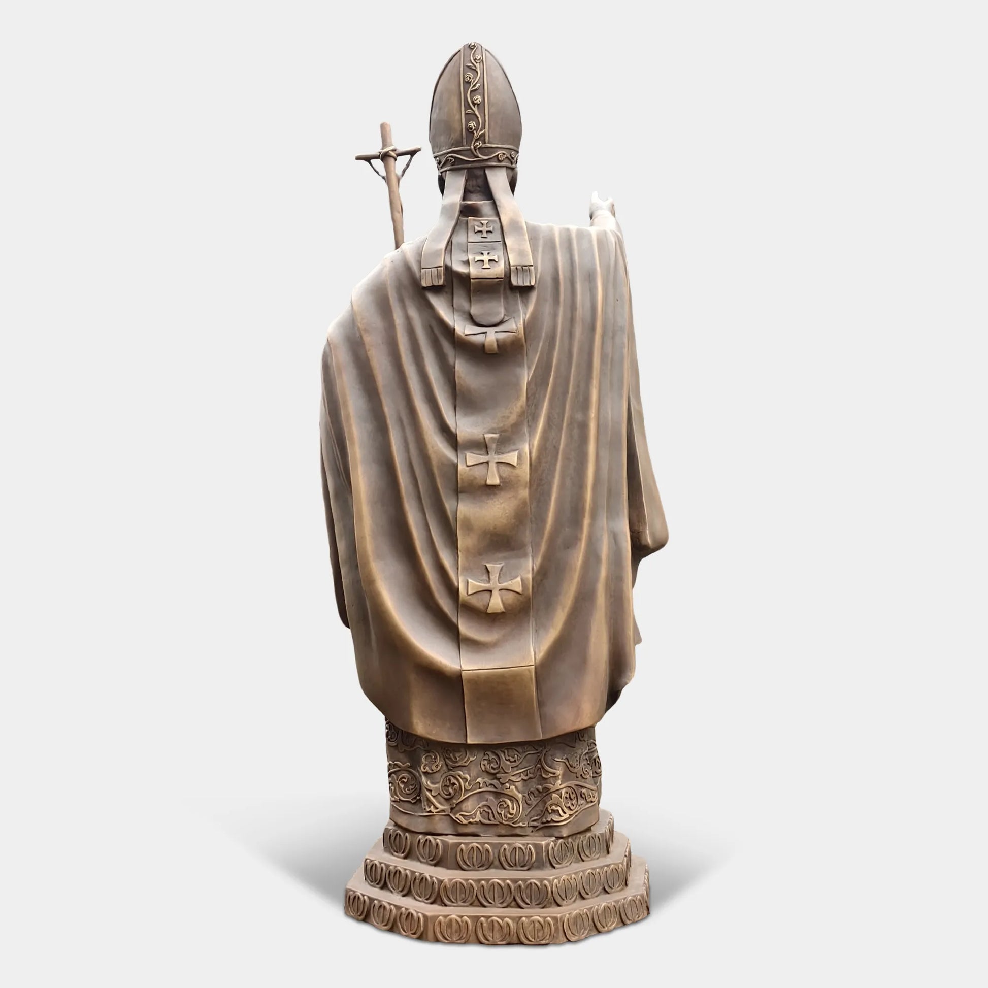 Bronze statue of a religious leader raising a hand in blessing.