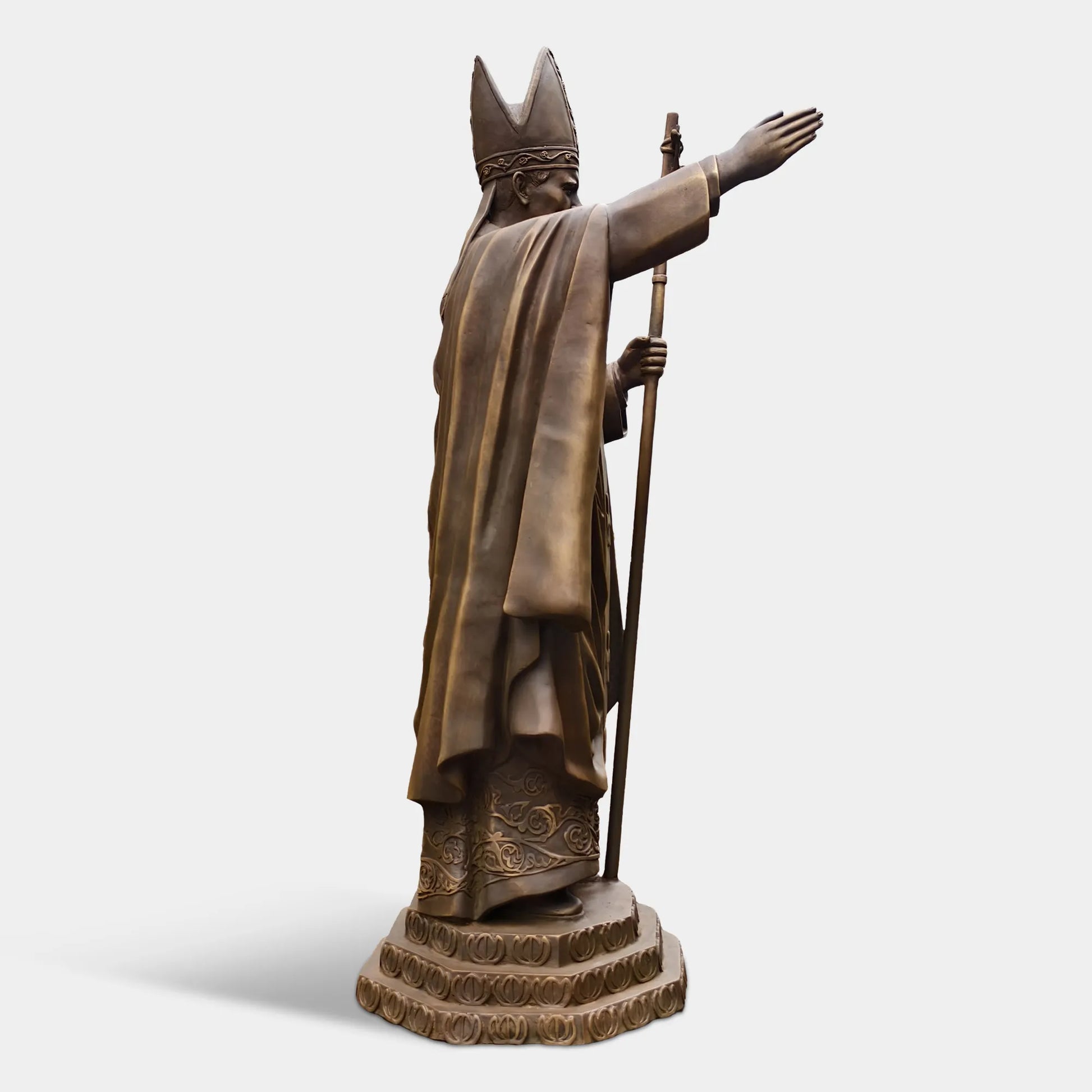Bronze statue of a religious leader raising a hand in blessing.