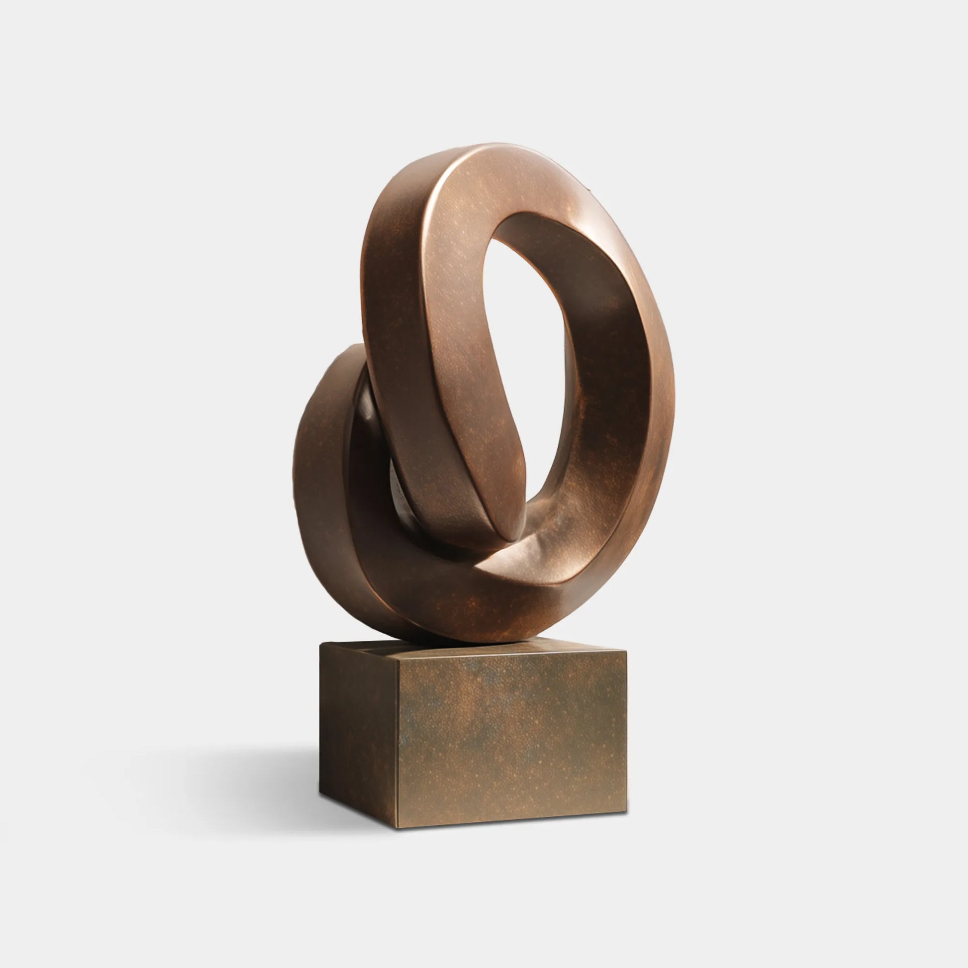 Interlocking bronze loop sculpture displayed in a modern interior.