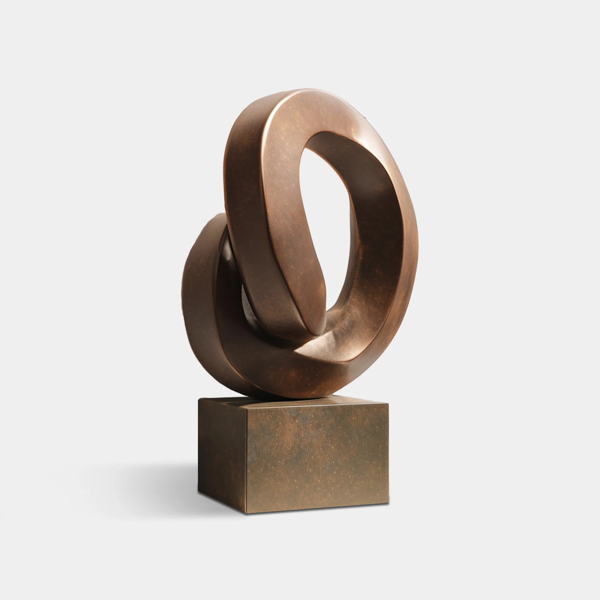Interlocking bronze loop sculpture displayed in a modern interior.