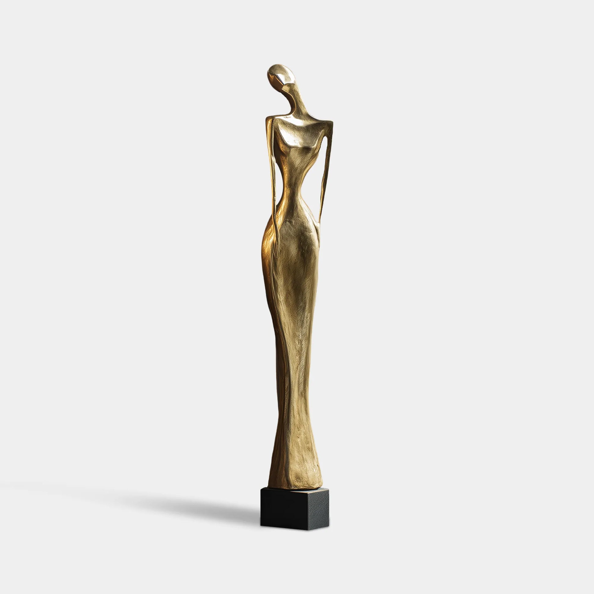 Bronze abstract figurative sculpture on black base beside bookshelf and window.