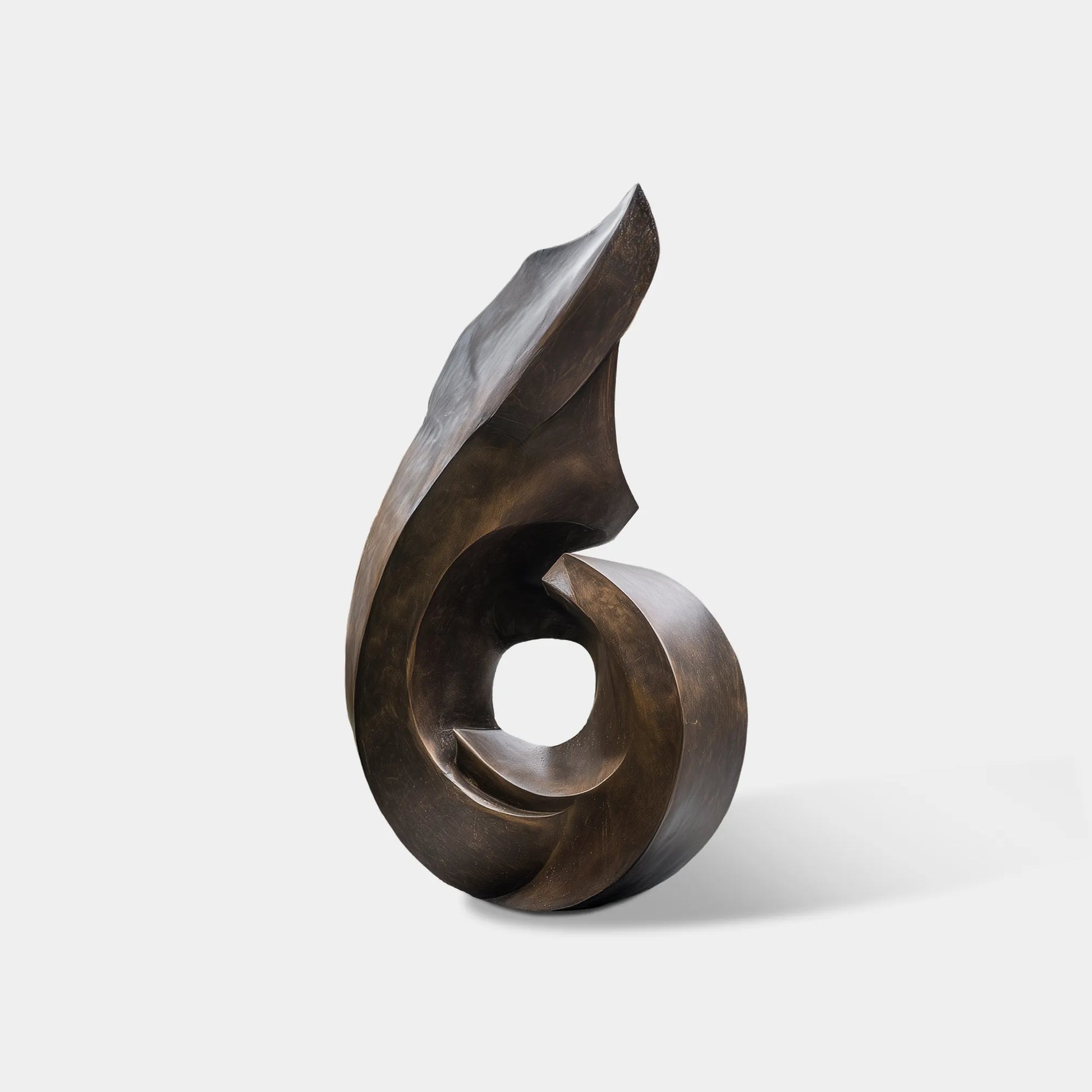 Abstract bronze spiral sculpture with smooth curved form and circular center on square pedestal in front yard entrance.