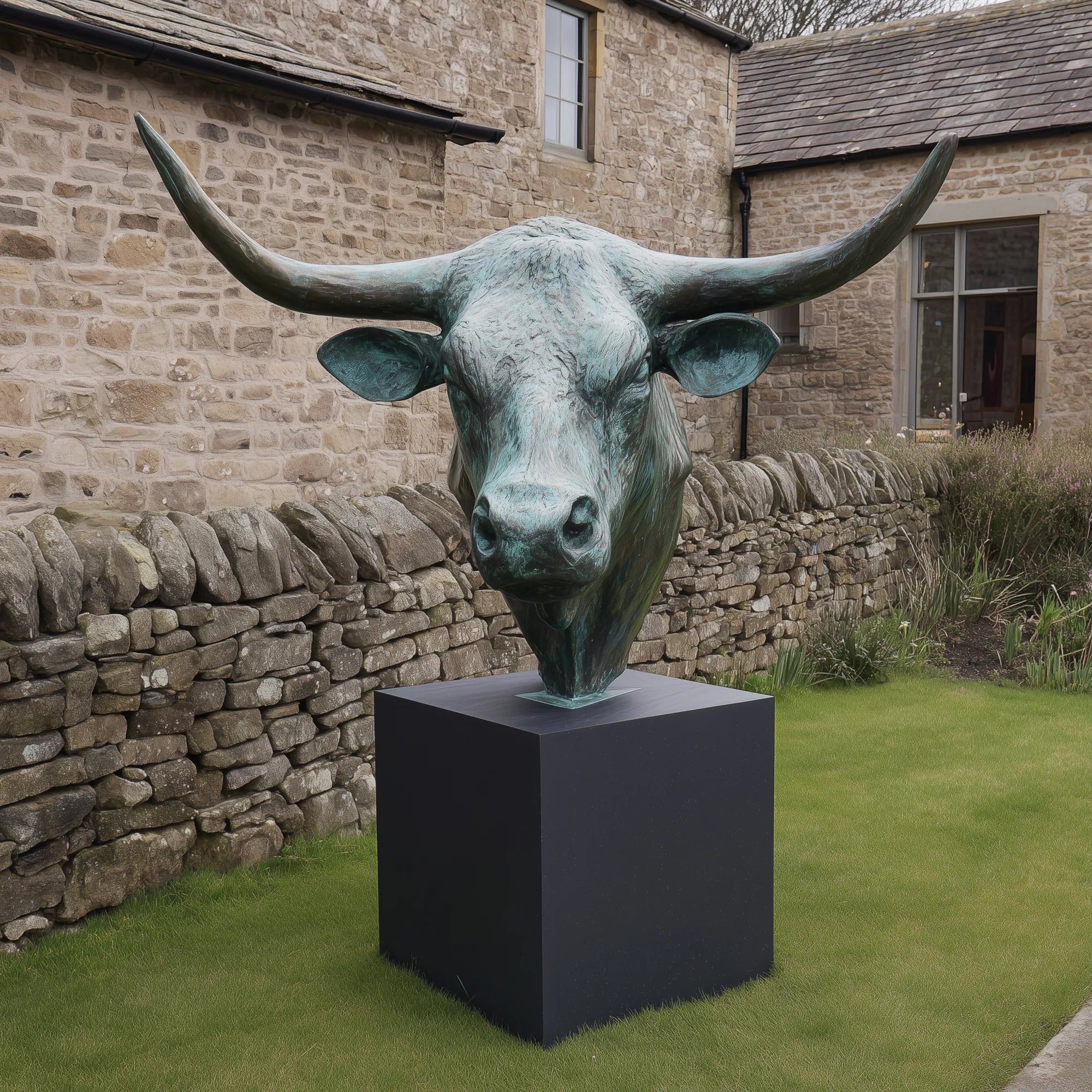 Bronze bull head sculpture in the corner of a backyard.