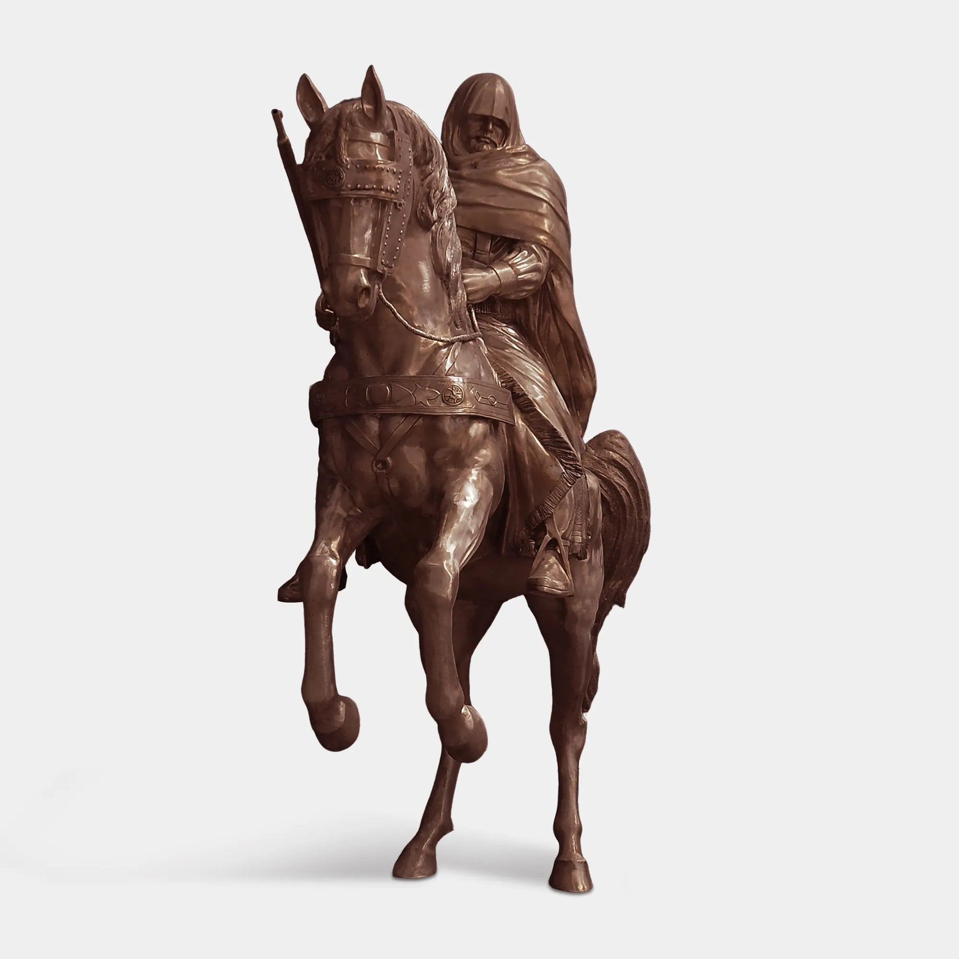 Bronze sculpture of a cloaked rider on a horse in dynamic motion in a villa garden.
