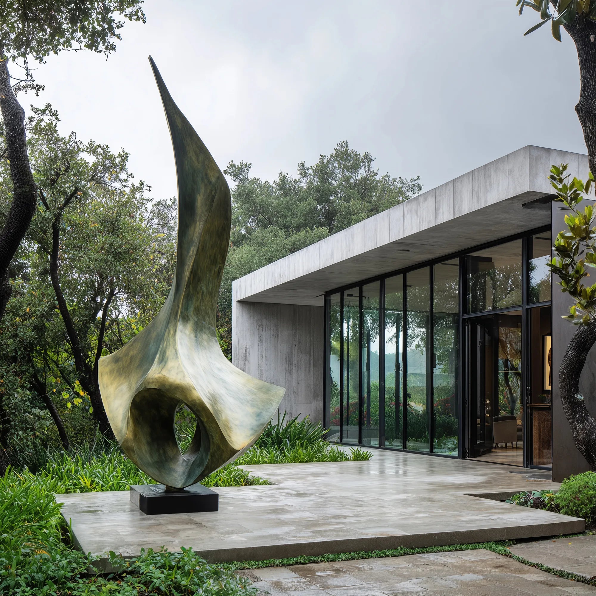 Bronze abstract sculpture beside a modern villa courtyard with glass walls and forest landscaping.
