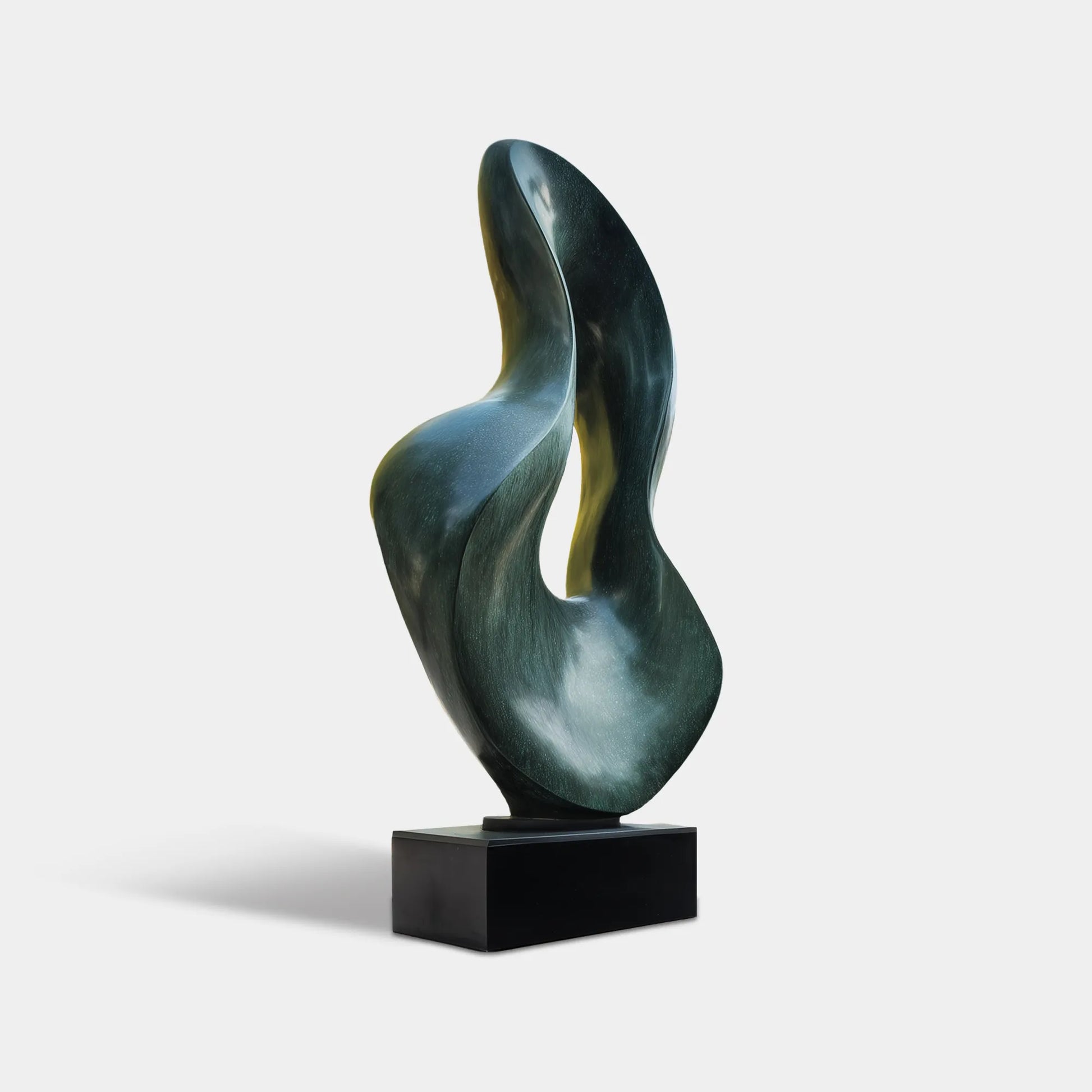 Dark bronze abstract sculpture with flowing organic curves in a modern villa courtyard beside a pool and glass architecture.