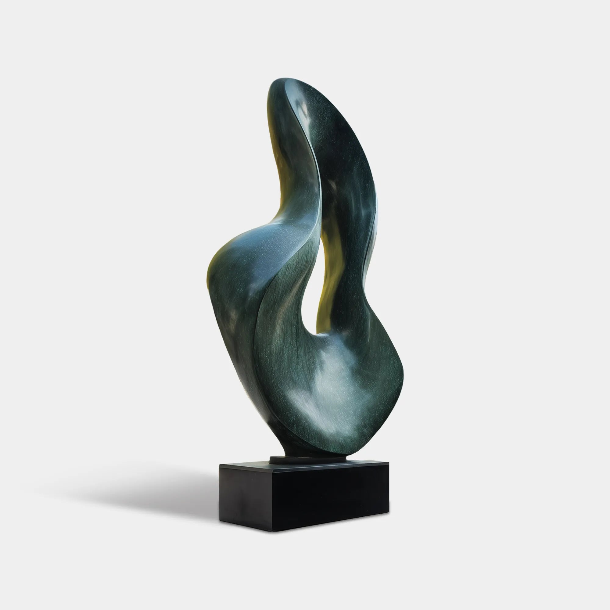 Dark bronze abstract sculpture with flowing organic curves in a modern villa courtyard beside a pool and glass architecture.