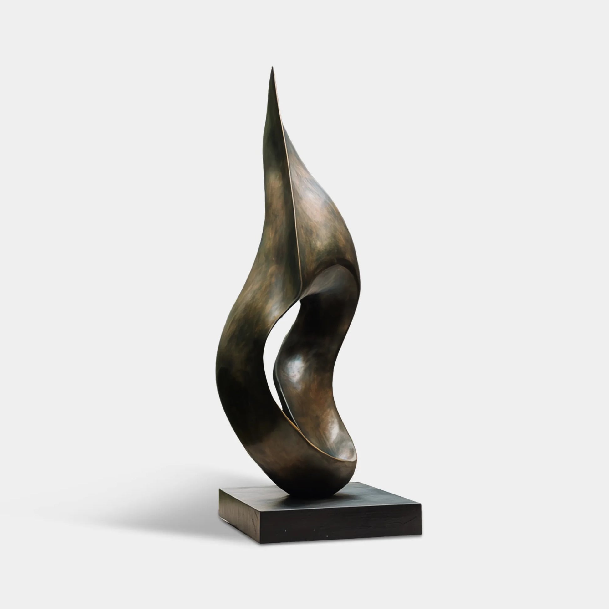 Dark bronze abstract flowing form sculpture beside modern glass house and garden pond.