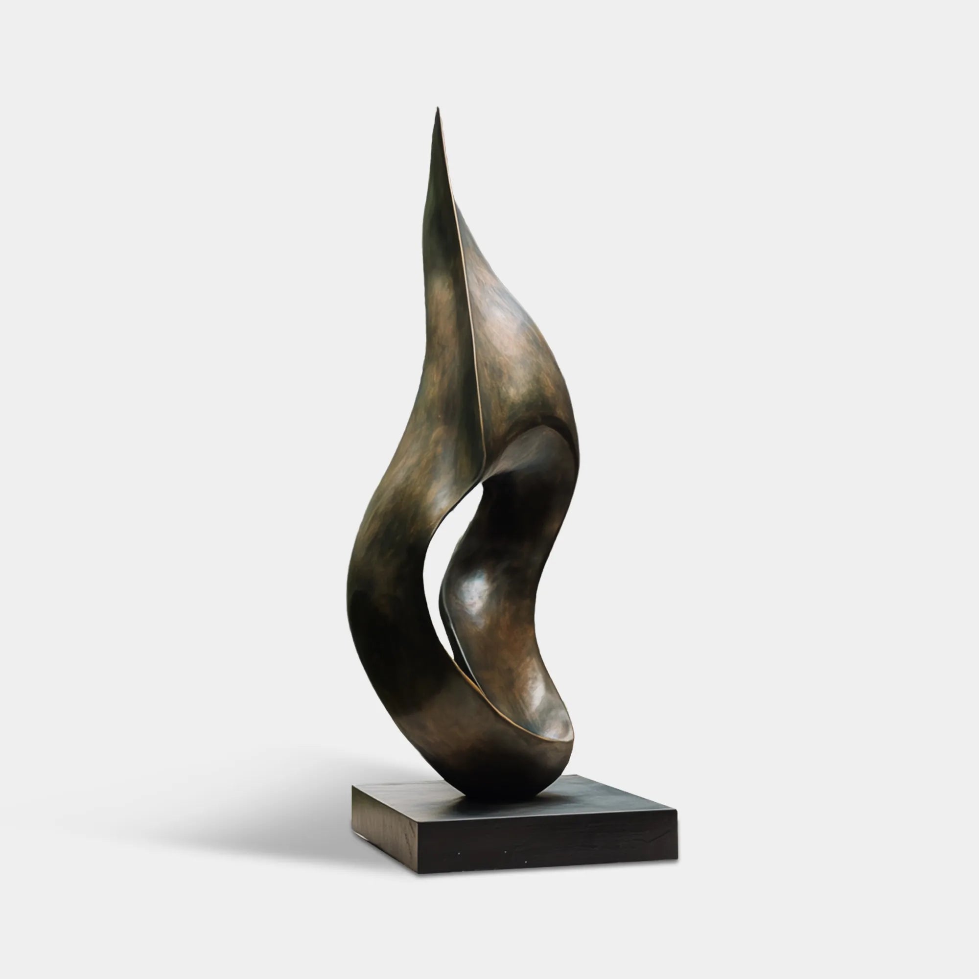 Dark bronze abstract flowing form sculpture beside modern glass house and garden pond.