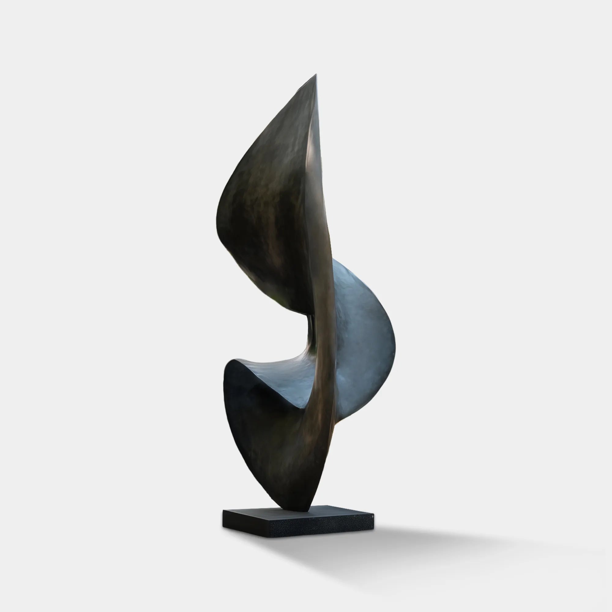Dark bronze abstract outdoor sculpture on a black base in a modern villa courtyard surrounded by trees.