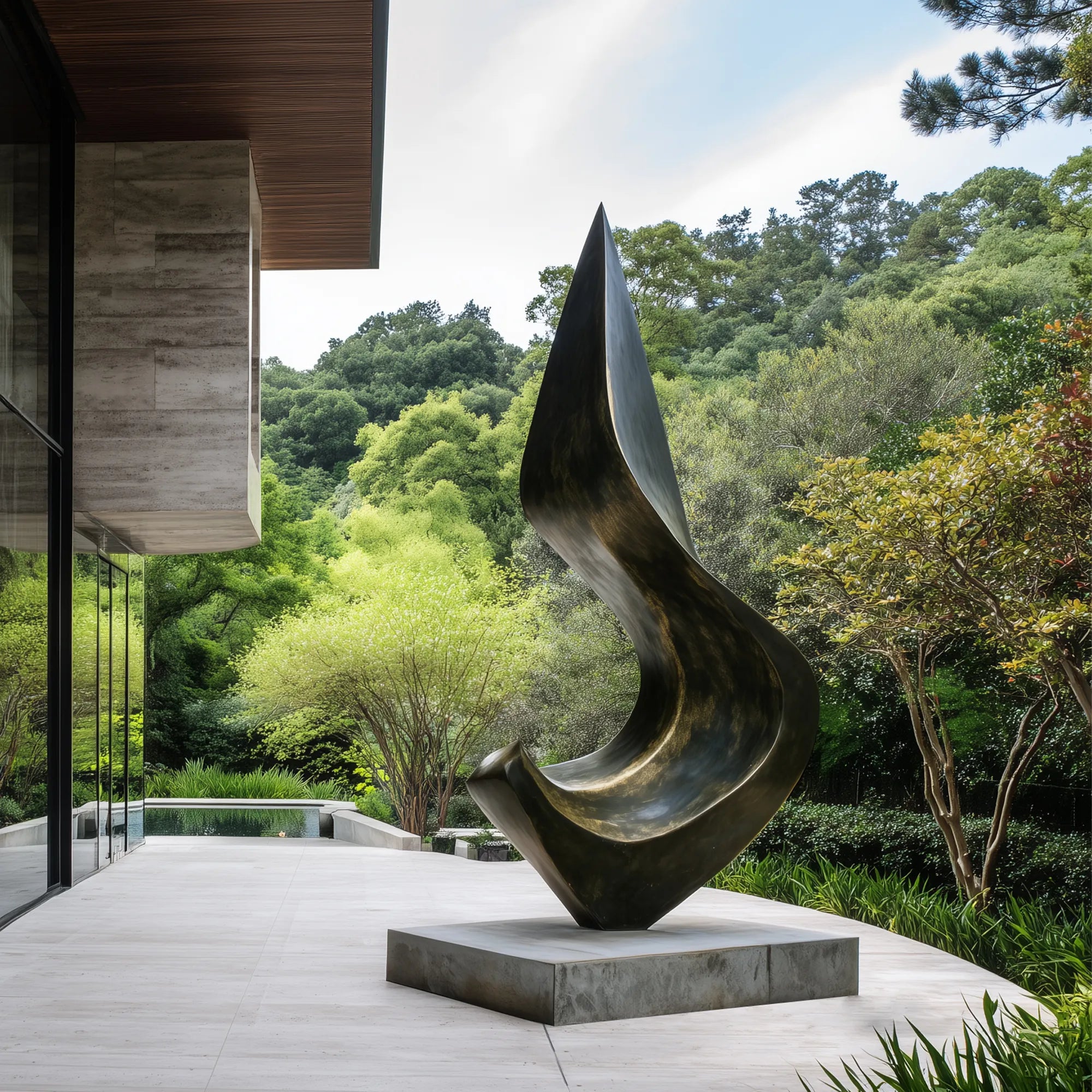 Dark bronze flowing form sculpture on a stone pedestal in a modern residence garden surrounded by trees and landscaped greenery.
