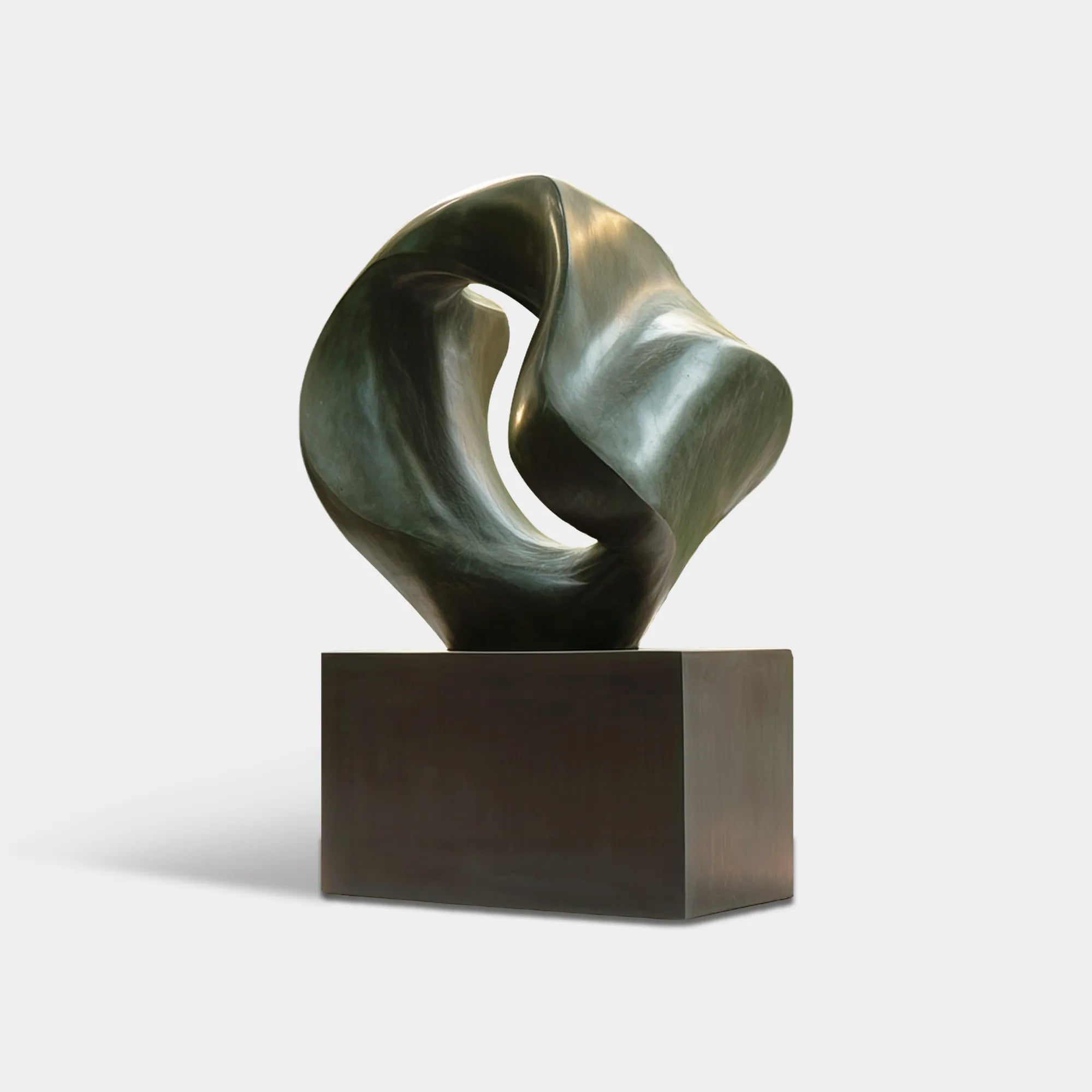 Dark bronze abstract sculpture with a rounded open form on a pedestal in a modern garden courtyard beside a contemporary residence.