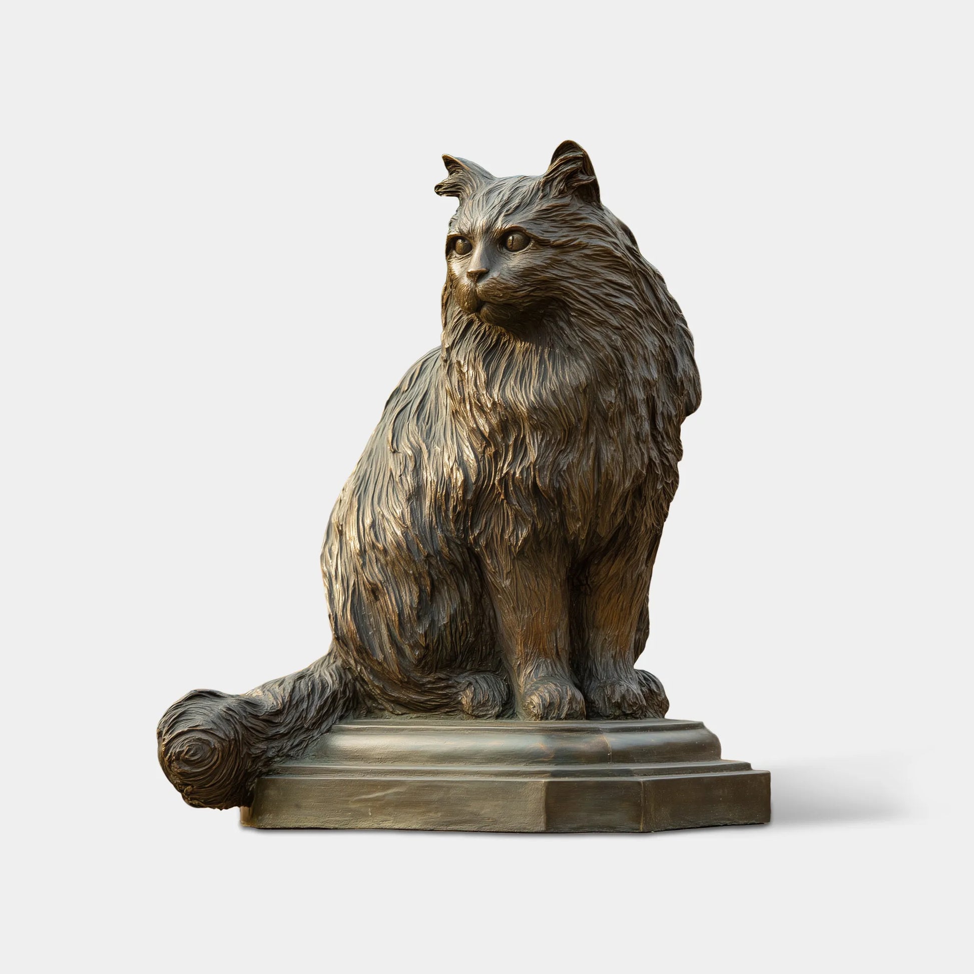 Bronze long-haired cat statue sitting on a pedestal beside a garden walkway and outdoor staircase.