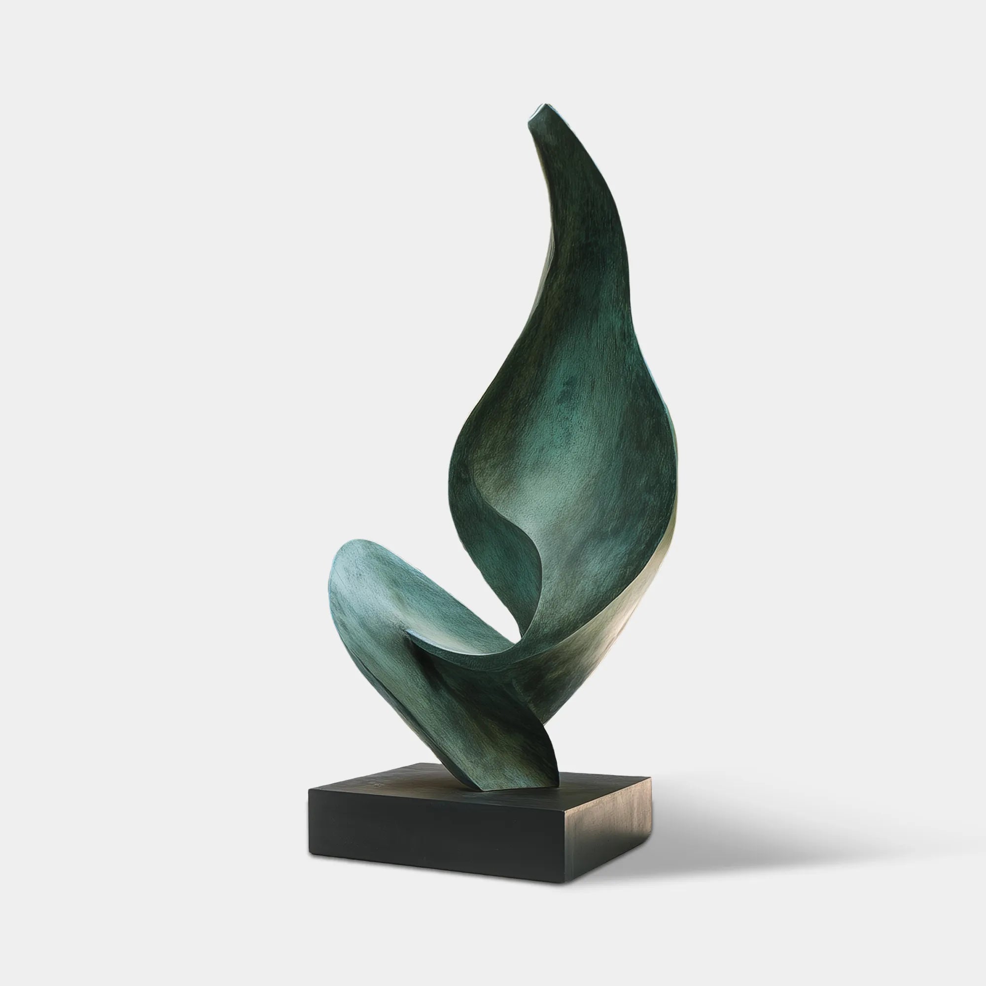 Abstract verdigris bronze sculpture with flowing organic form on a black pedestal in a luxury villa courtyard.