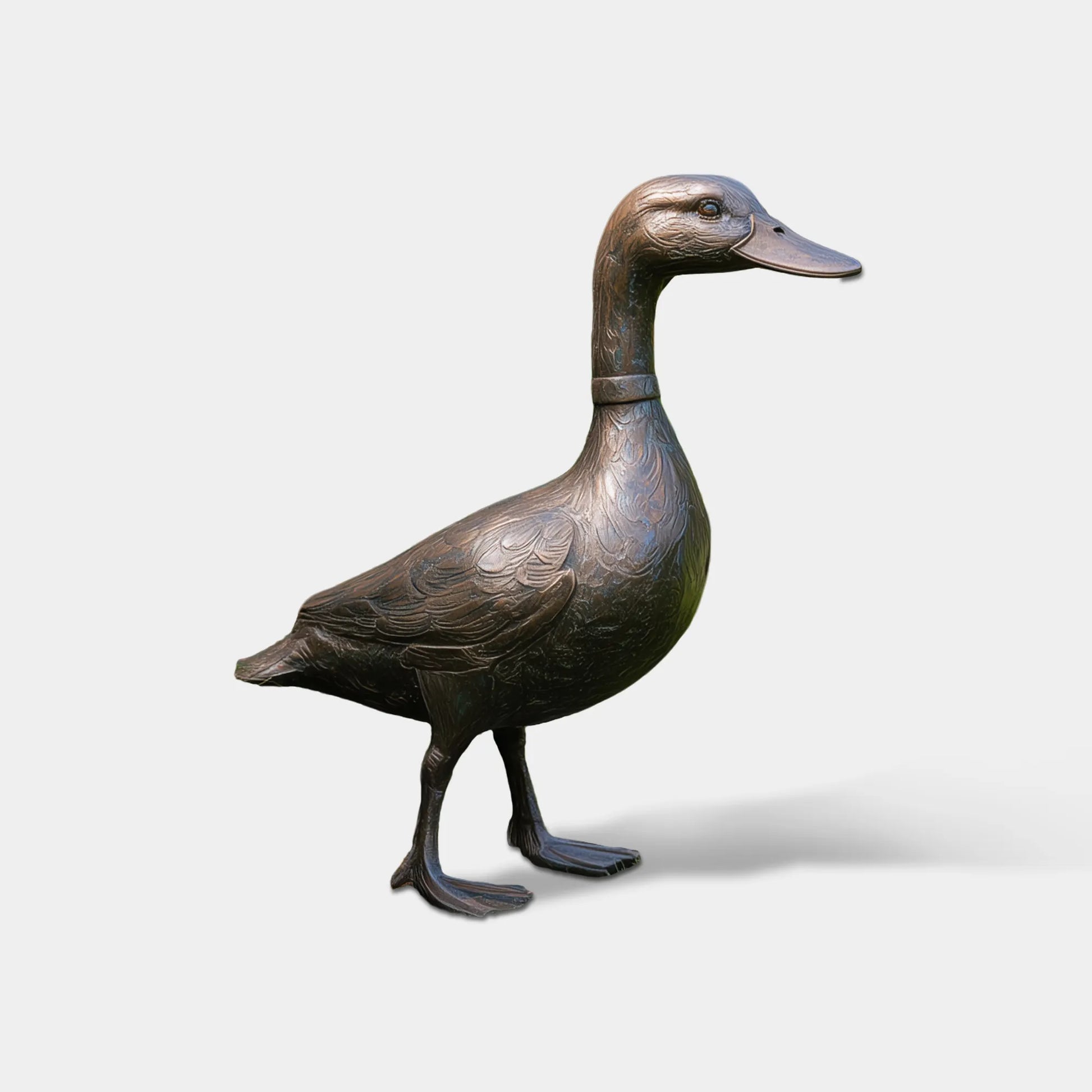 A bronze standing duck sculpture sits on green lawn beside pink rose bushes near a residential front door.