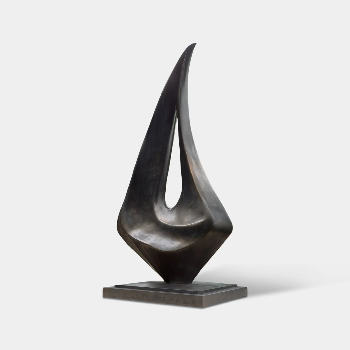 Large dark bronze abstract sculpture with an asymmetrical organic form and central opening in a modern residential garden courtyard