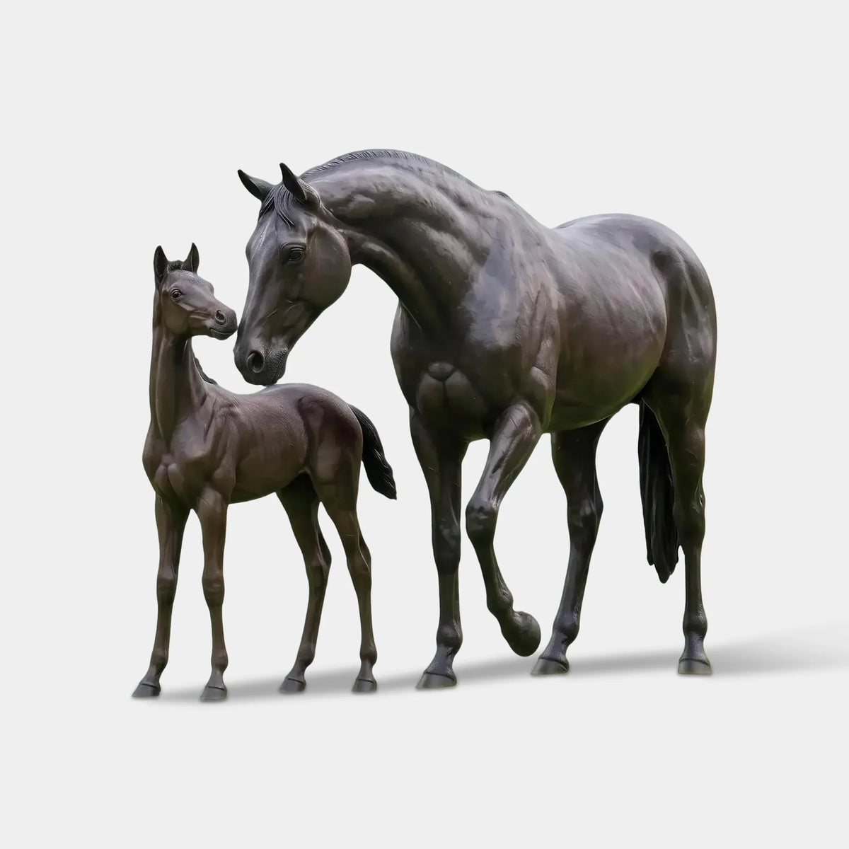 The bronze mare and foal statue are on a green lawn with tall trees in the background.