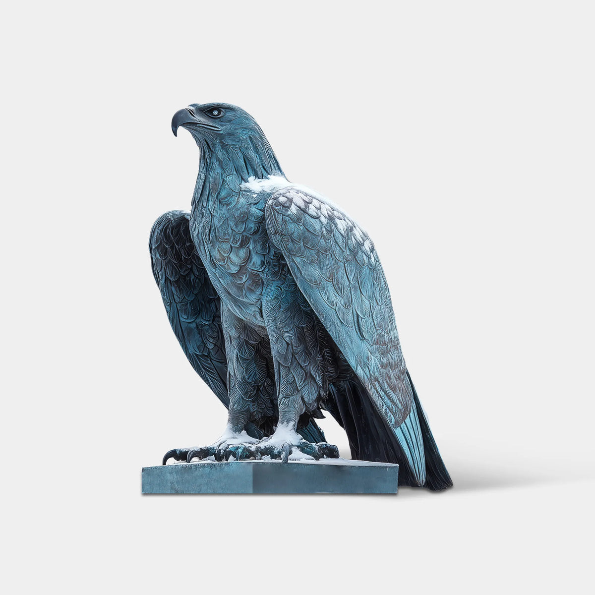 Bronze eagle sculpture with detailed feathers, curved beak and powerful talons on a stone pedestal in a snow-covered outdoor park.