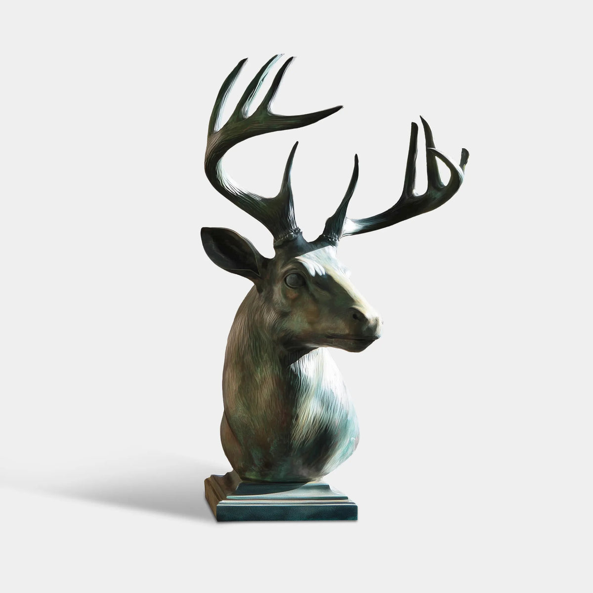 Large bronze deer bust sculpture with branching antlers, realistic facial details and green patina finish beside floor-to-ceiling windows.