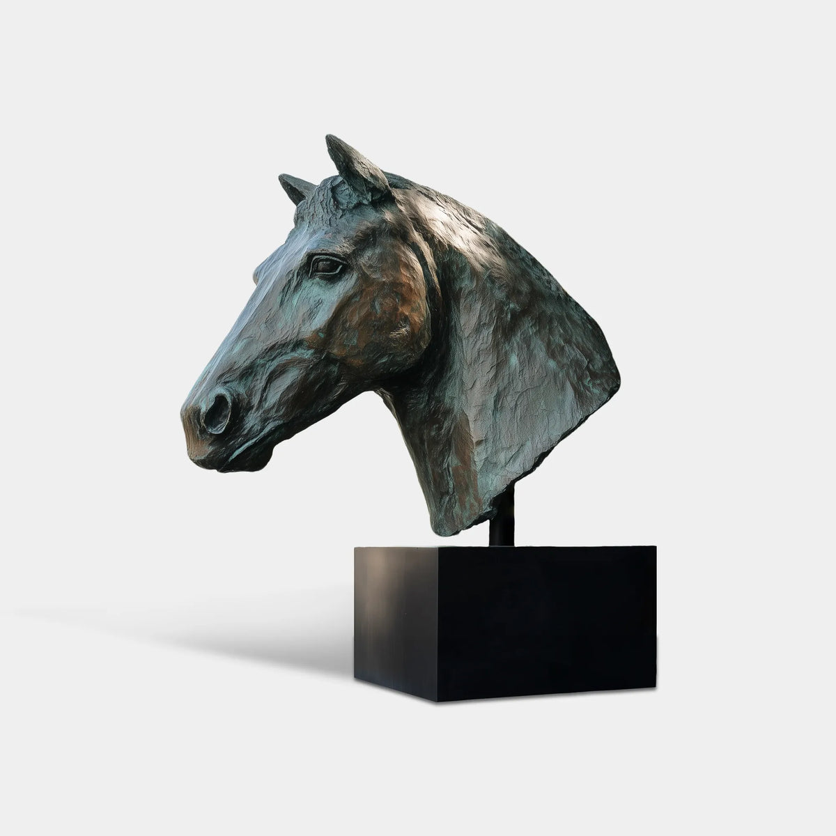 Large bronze horse head bust sculpture with textured mane and green patina finish in a landscaped country house garden.