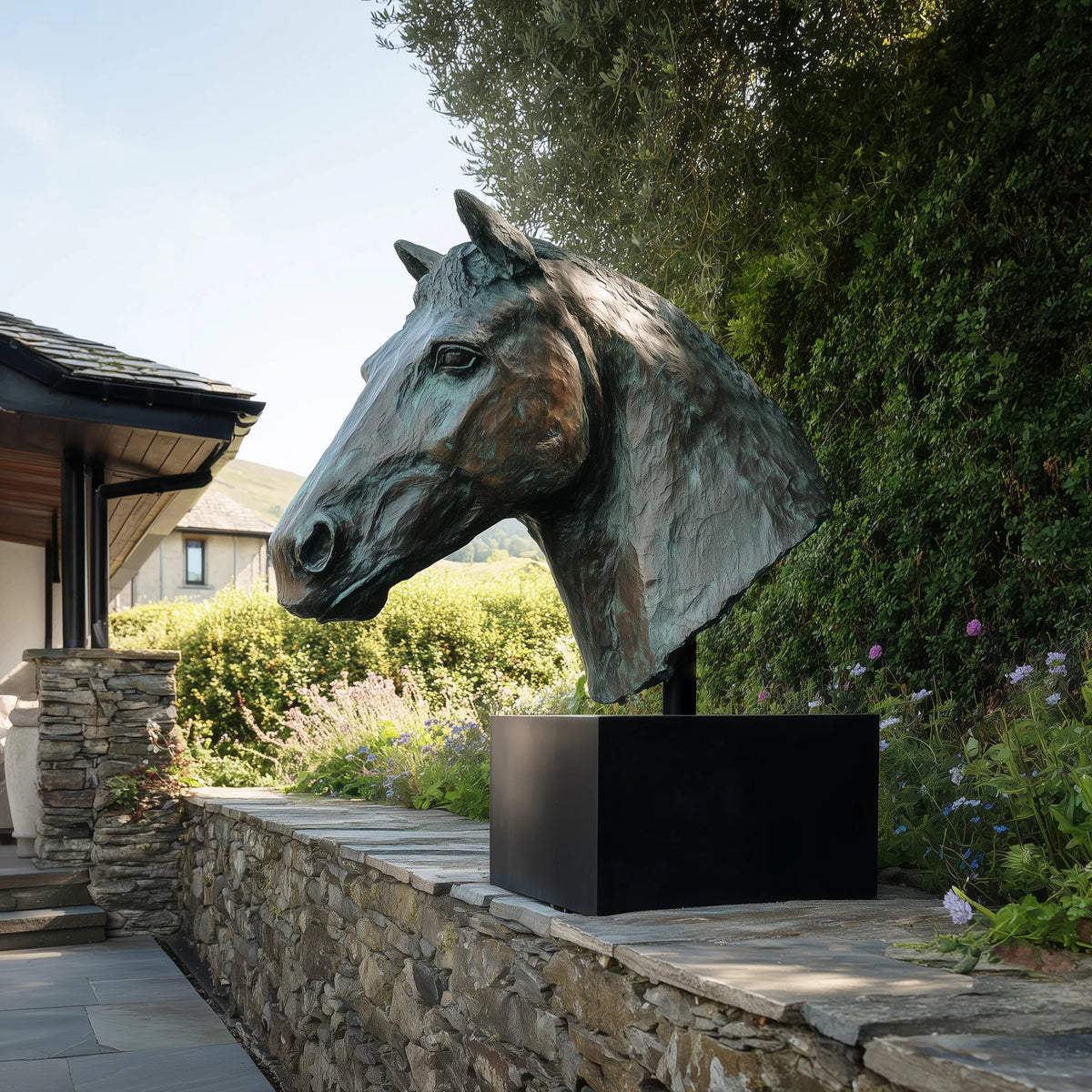Large bronze horse head bust sculpture with textured mane and green patina finish in a landscaped country house garden.